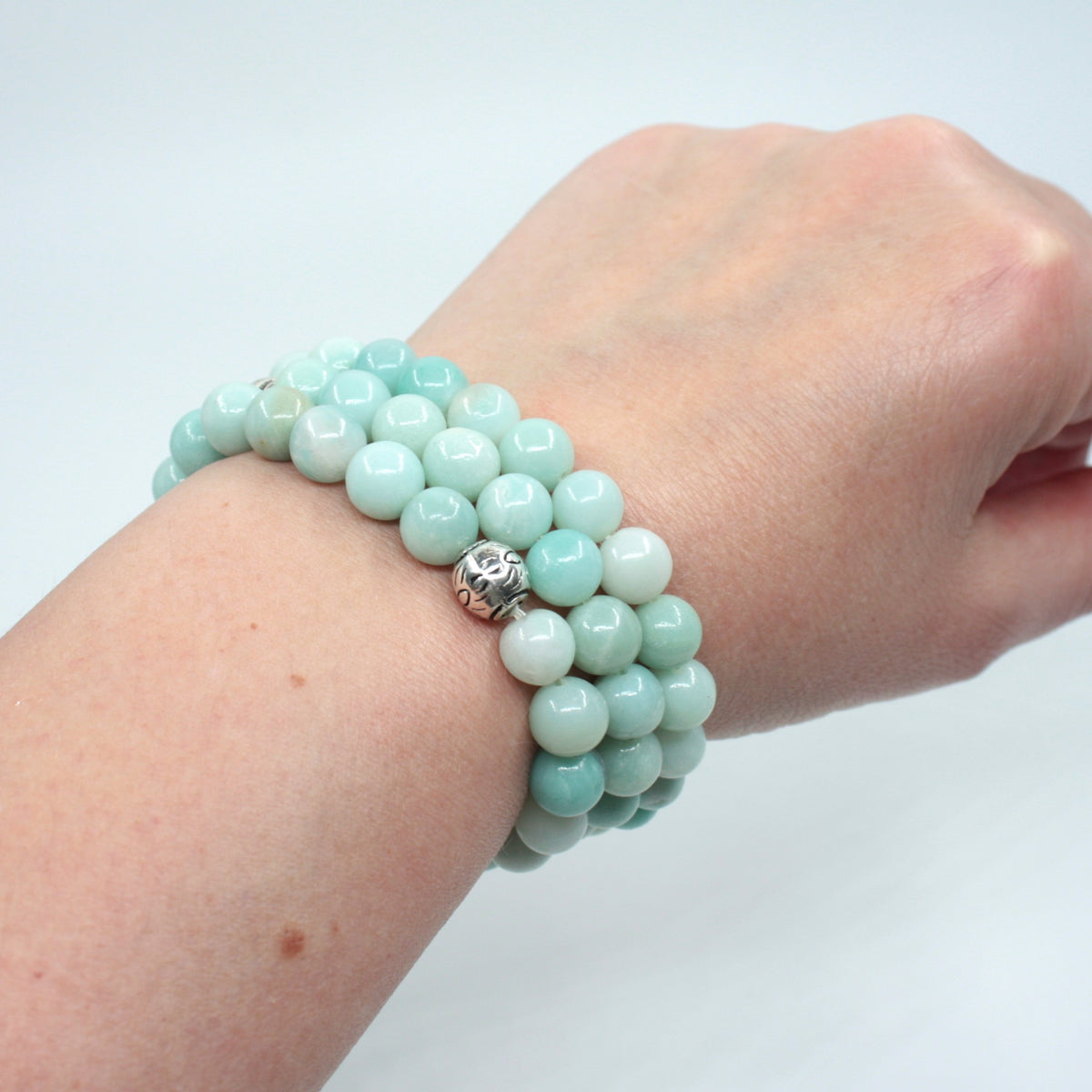 Kolme amatsoniitti rannekorua ranteessa. Tausta on valkoinen. Three amazonite bracelets on the wrist. Background is white.