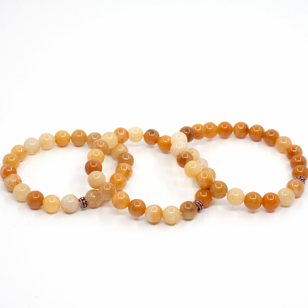 Kolme keltainen jade rannekorua valkoisella alustalla. Three yellow jade bracelets on a white surface. 