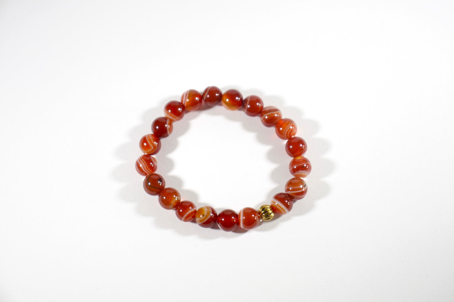 Agate orange tones stretch bracelet with gold color bead. Akaatti jousto rannekoru lämpimän oranssin sävyissä. Korussa on yksi kullan värinen korumetalli helmi. 