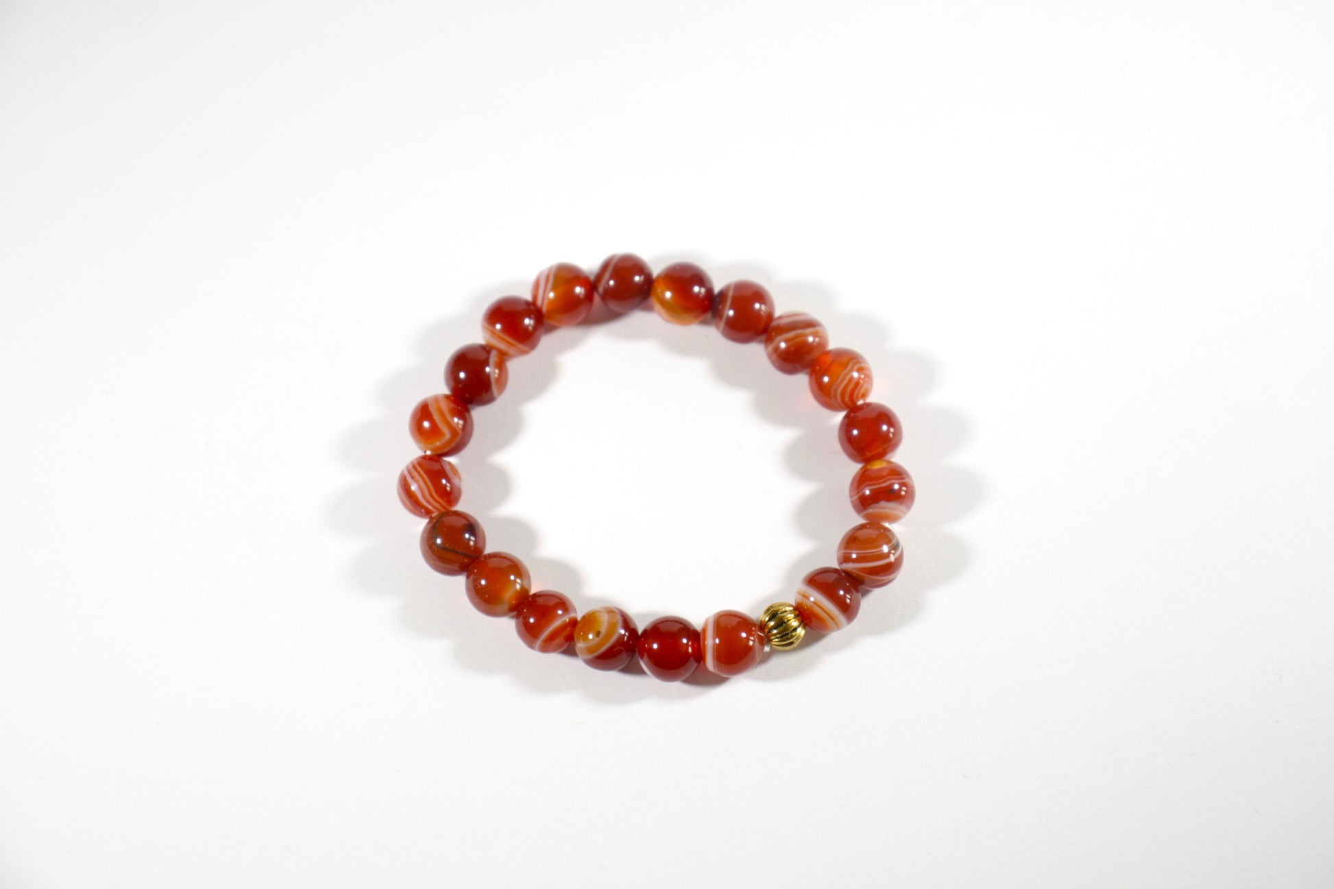Agate orange tones stretch bracelet with gold color bead. Akaatti jousto rannekoru lämpimän oranssin sävyissä. Korussa on yksi kullan värinen korumetalli helmi. 
