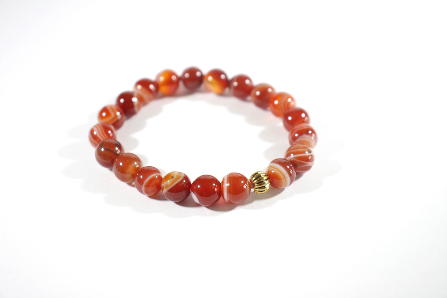 Agate orange tones stretch bracelet with gold color bead. Akaatti jousto rannekoru lämpimän oranssin sävyissä. Korussa on yksi kullan värinen korumetalli helmi. 