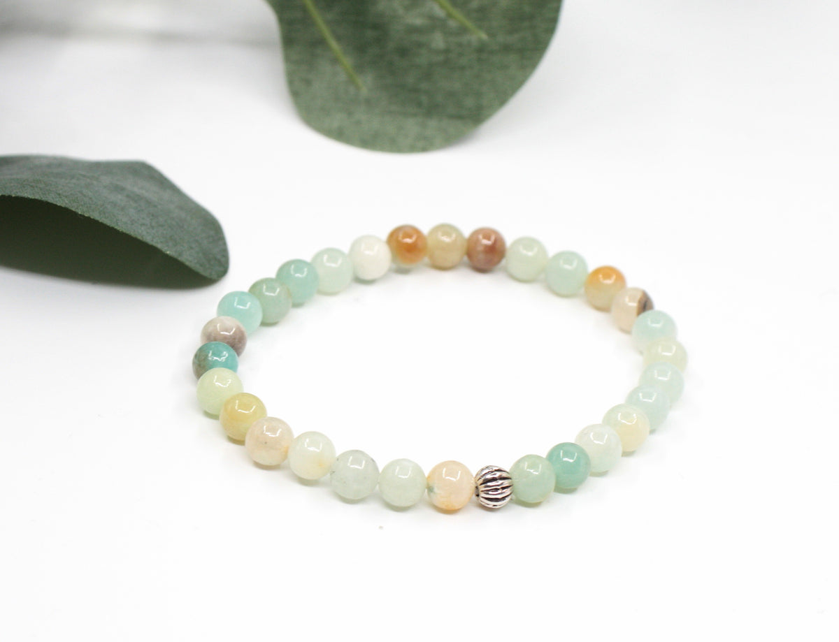 Amazonite beads stretchy bracelet on the white background. Green leaves behind. Amatsoniittihelmi joustava rannekoru valkoisella pohjalla. Taustalla vihreitä lehtiä.