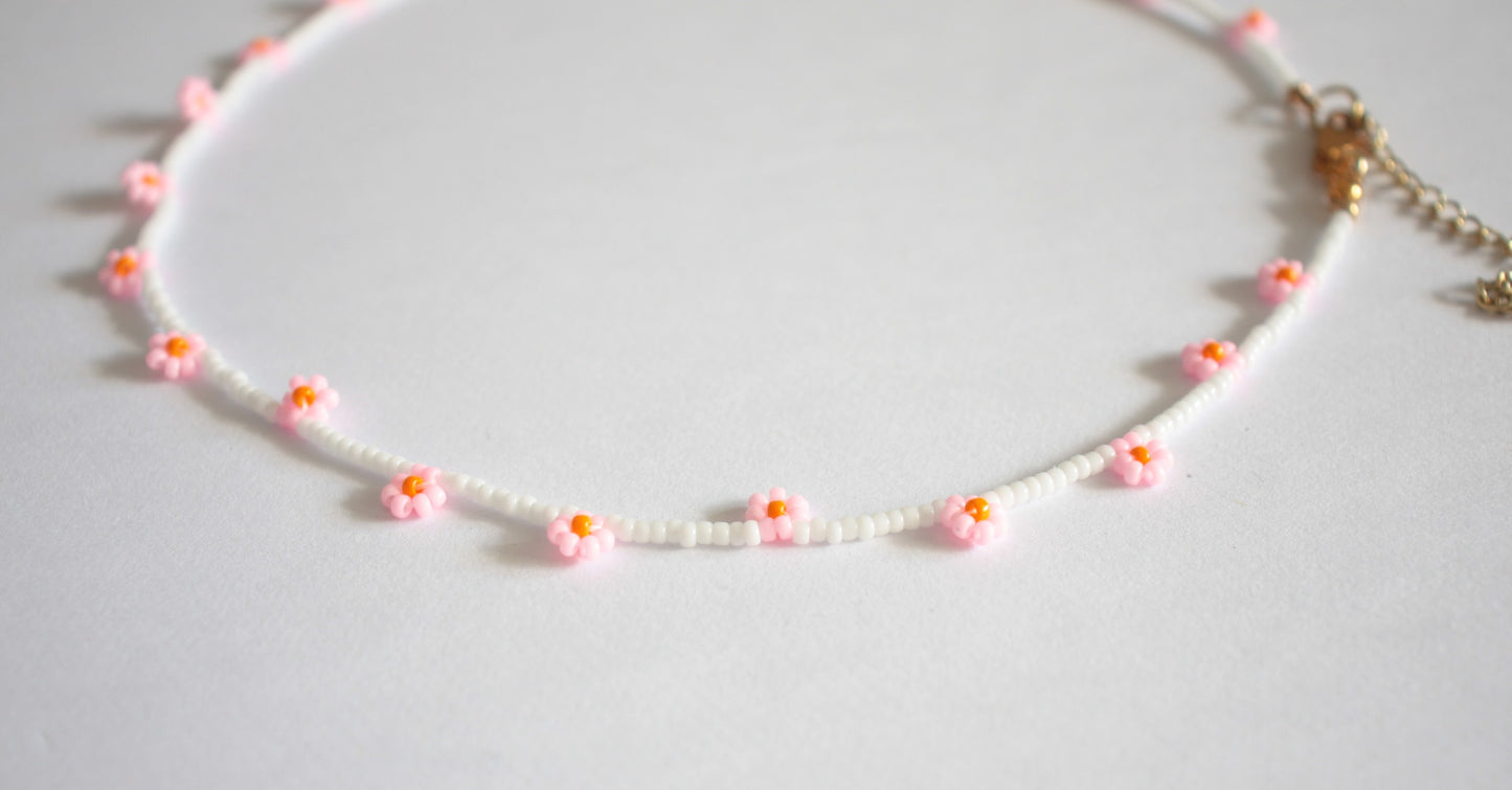 Daisy chain choker necklace white with pink and orange flowers. Päivänkakkara daisy chain choker kaulakoru valkoinen vaaleanpunaisilla kukilla. Kukkien keskusta on oranssi.