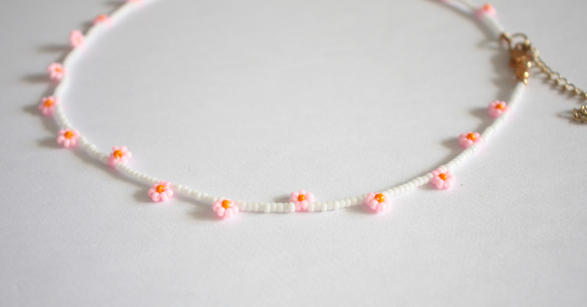 Daisy chain choker necklace white with pink and orange flowers. Päivänkakkara daisy chain choker kaulakoru valkoinen vaaleanpunaisilla kukilla. Kukkien keskusta on oranssi.