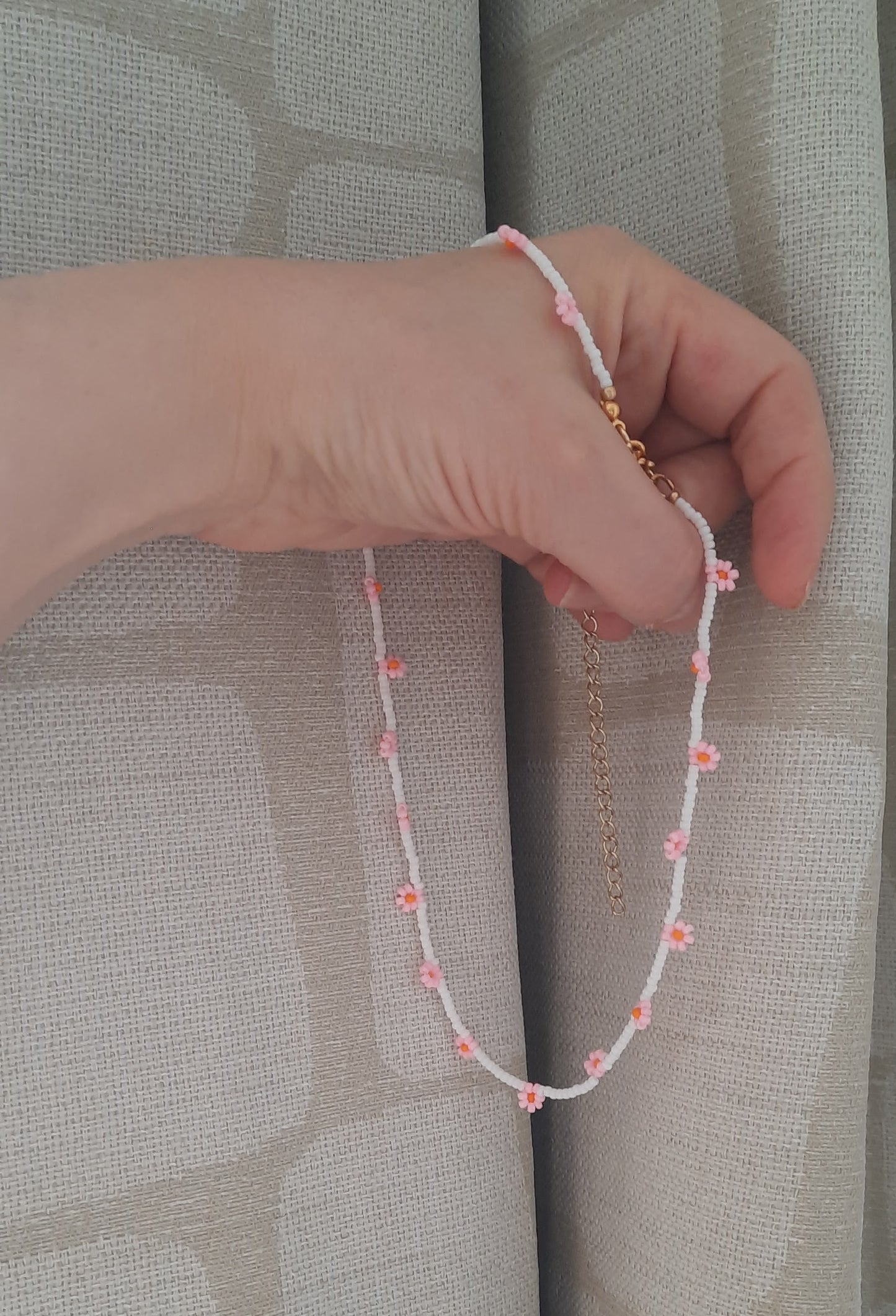 Daisy chain choker necklace white with pink and orange flowers. Päivänkakkara daisy chain choker kaulakoru valkoinen vaaleanpunaisilla kukilla. Kukkien keskusta on oranssi.