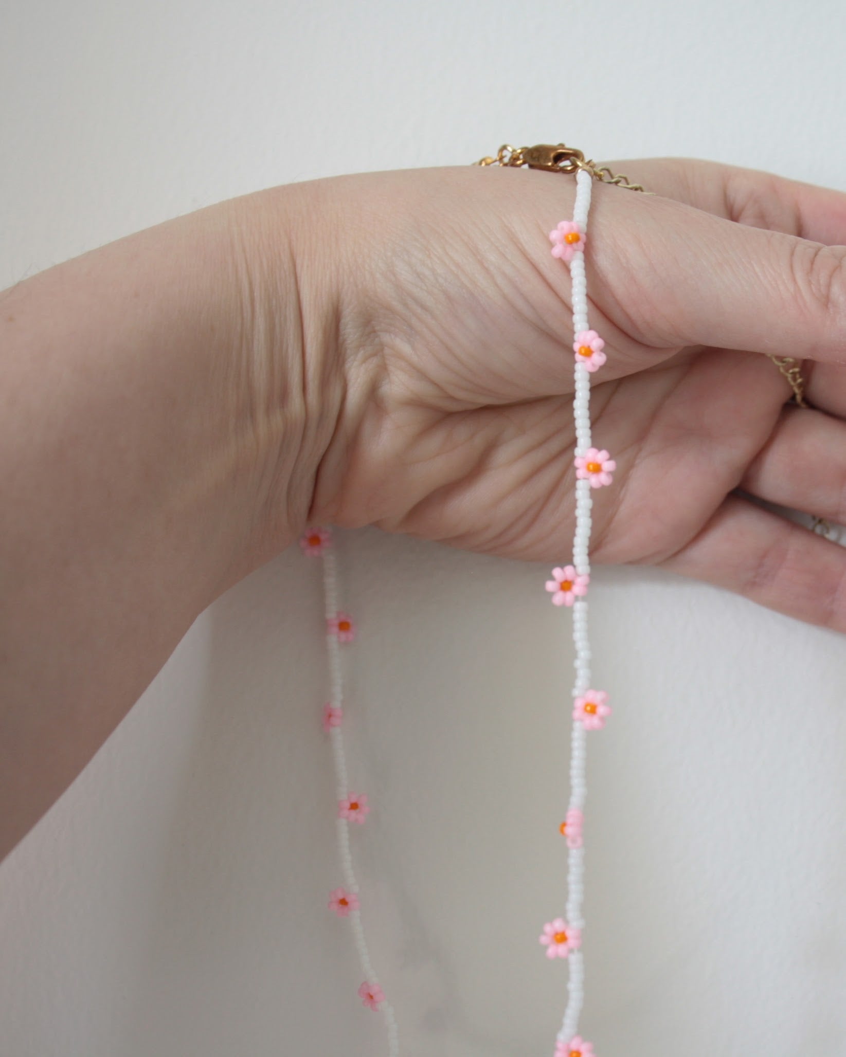 Daisy chain choker necklace white with pink and orange flowers. Päivänkakkara daisy chain choker kaulakoru valkoinen vaaleanpunaisilla kukilla. Kukkien keskusta on oranssi.