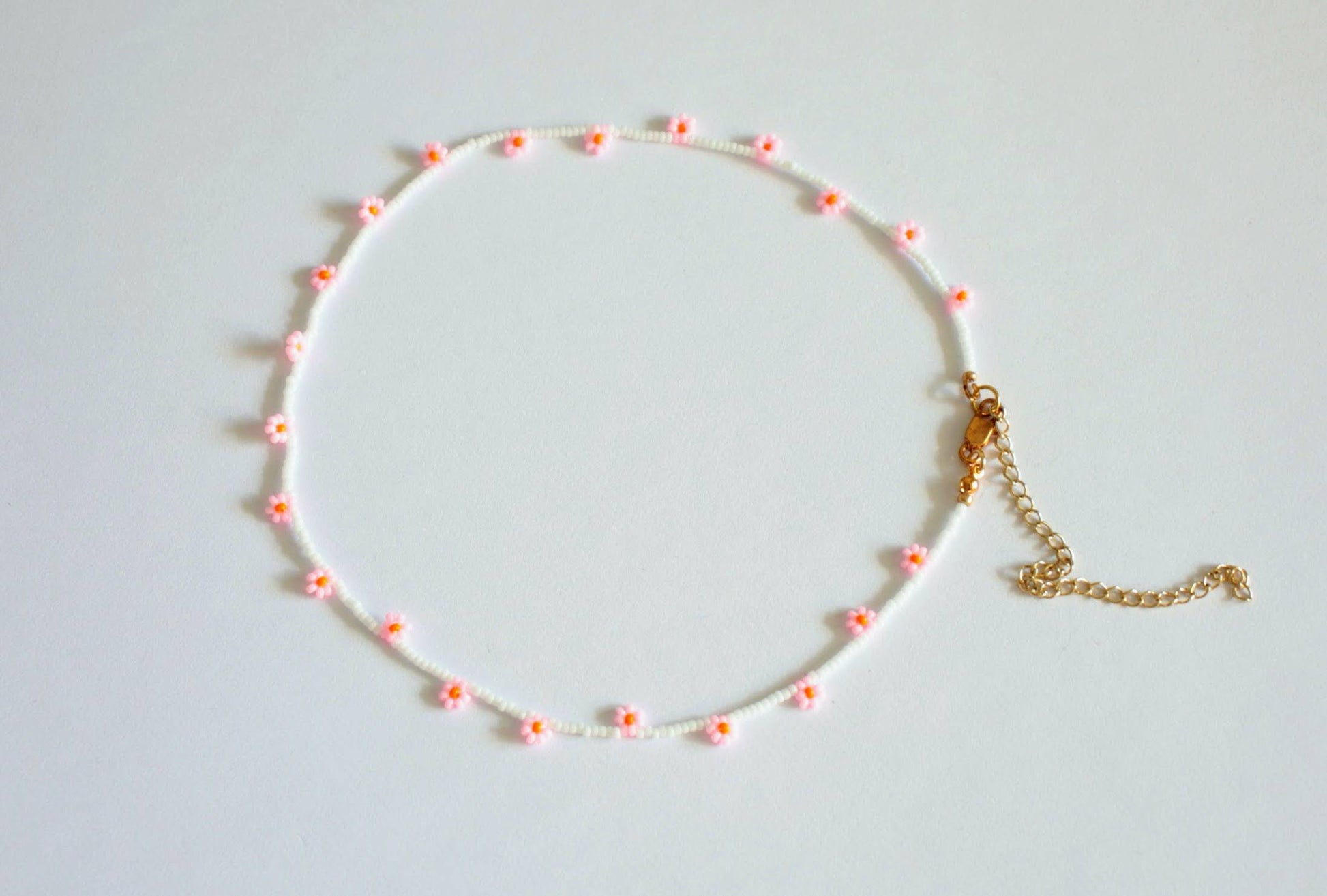 Daisy chain choker necklace white with pink and orange flowers. Päivänkakkara daisy chain choker kaulakoru valkoinen vaaleanpunaisilla kukilla. Kukkien keskusta on oranssi.