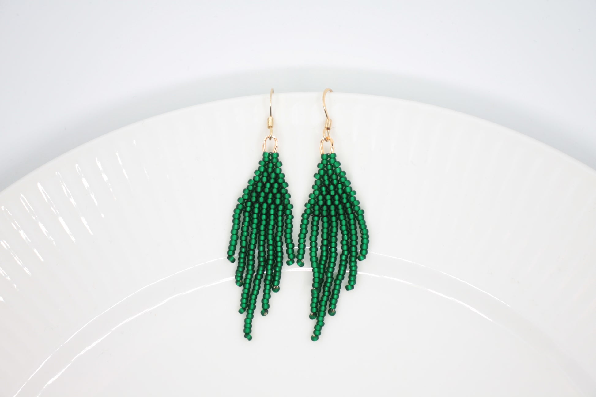 Hapsulliset helmikorvakorut valkoisella alustalla. Korvakorujen väri on matta vihreä. Seed bead fringe earrings on white background. Earrings color is matte green
