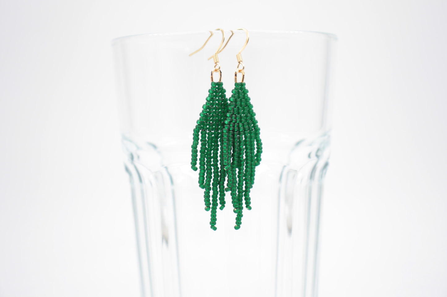 Hapsulliset helmikorvakorut valkoisella alustalla. Korvakorujen väri on matta vihreä. Seed bead fringe earrings on white background. Earrings color is matte green