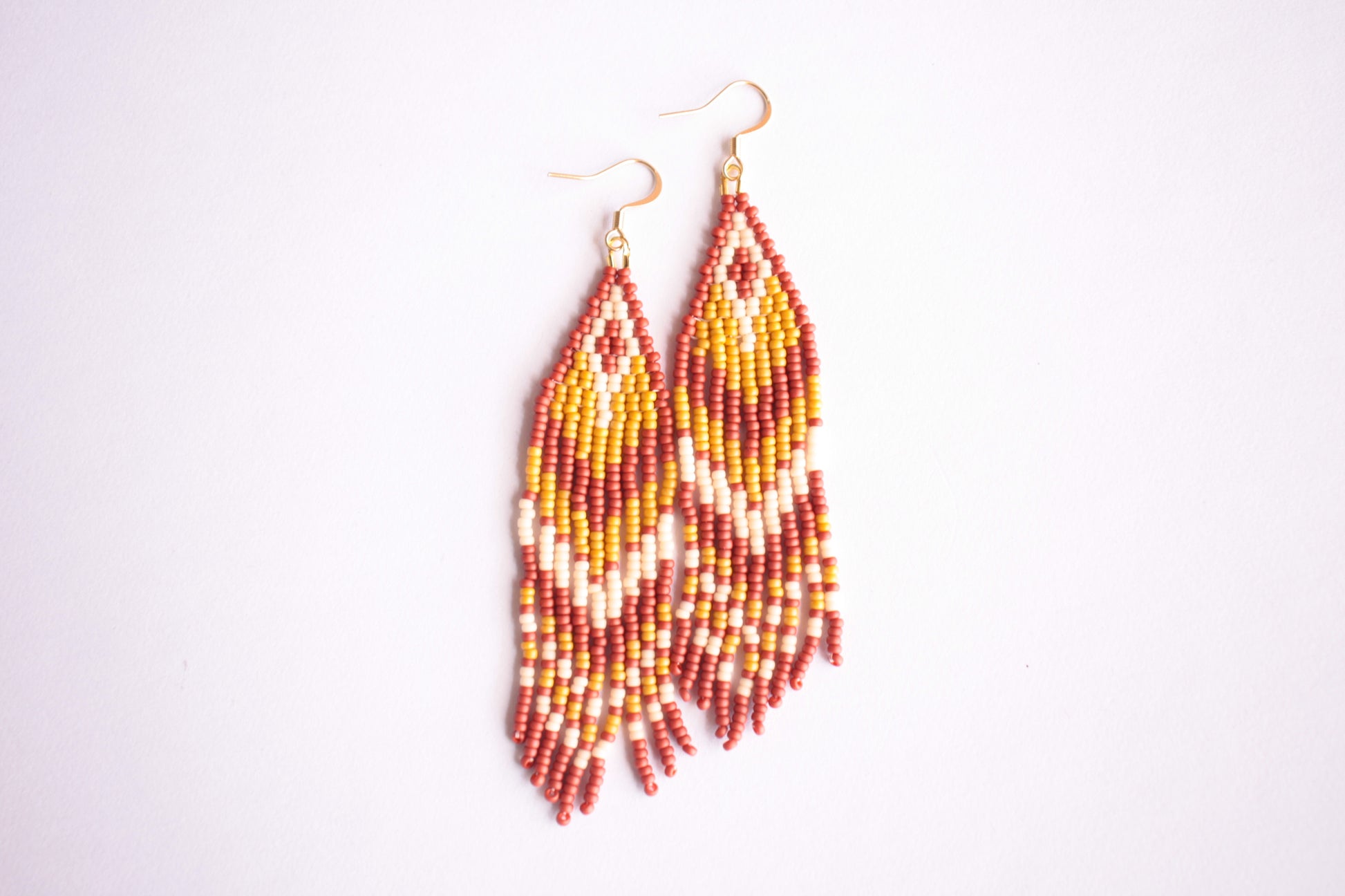Roikkuvat hapsulliset raidalliset helmikorvakorut lasihelmillä ruskean sävyissä. Beaded seed bead striped fringe earrings in shades of brown.