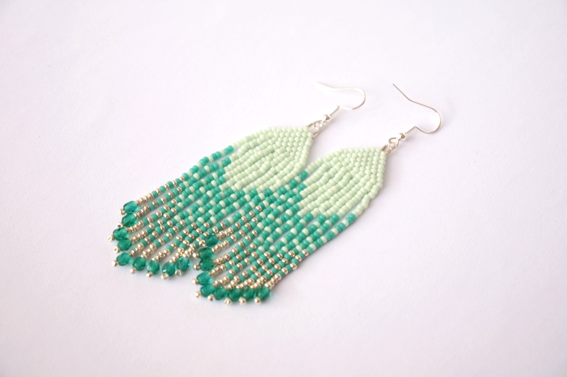 Hapsulliset kotimaiset roikkuvat helmikorvakorut mintun ja turkoosin sävyissä. Beaded seed bead fringe earrings with mint and turquoise colors.