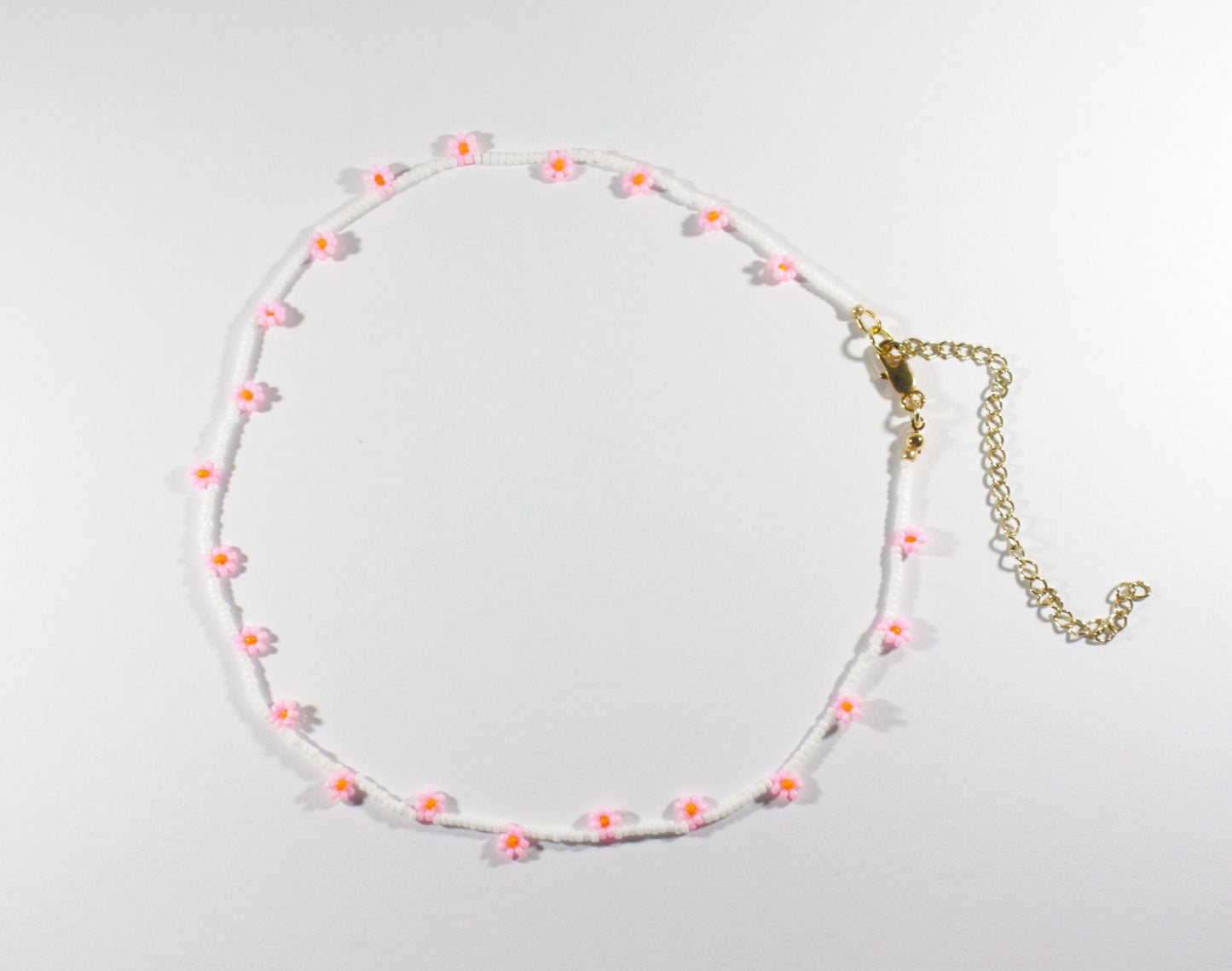 Daisy chain choker necklace white with pink and orange flowers. Päivänkakkara daisy chain choker kaulakoru valkoinen vaaleanpunaisilla kukilla. Kukkien keskusta on oranssi.