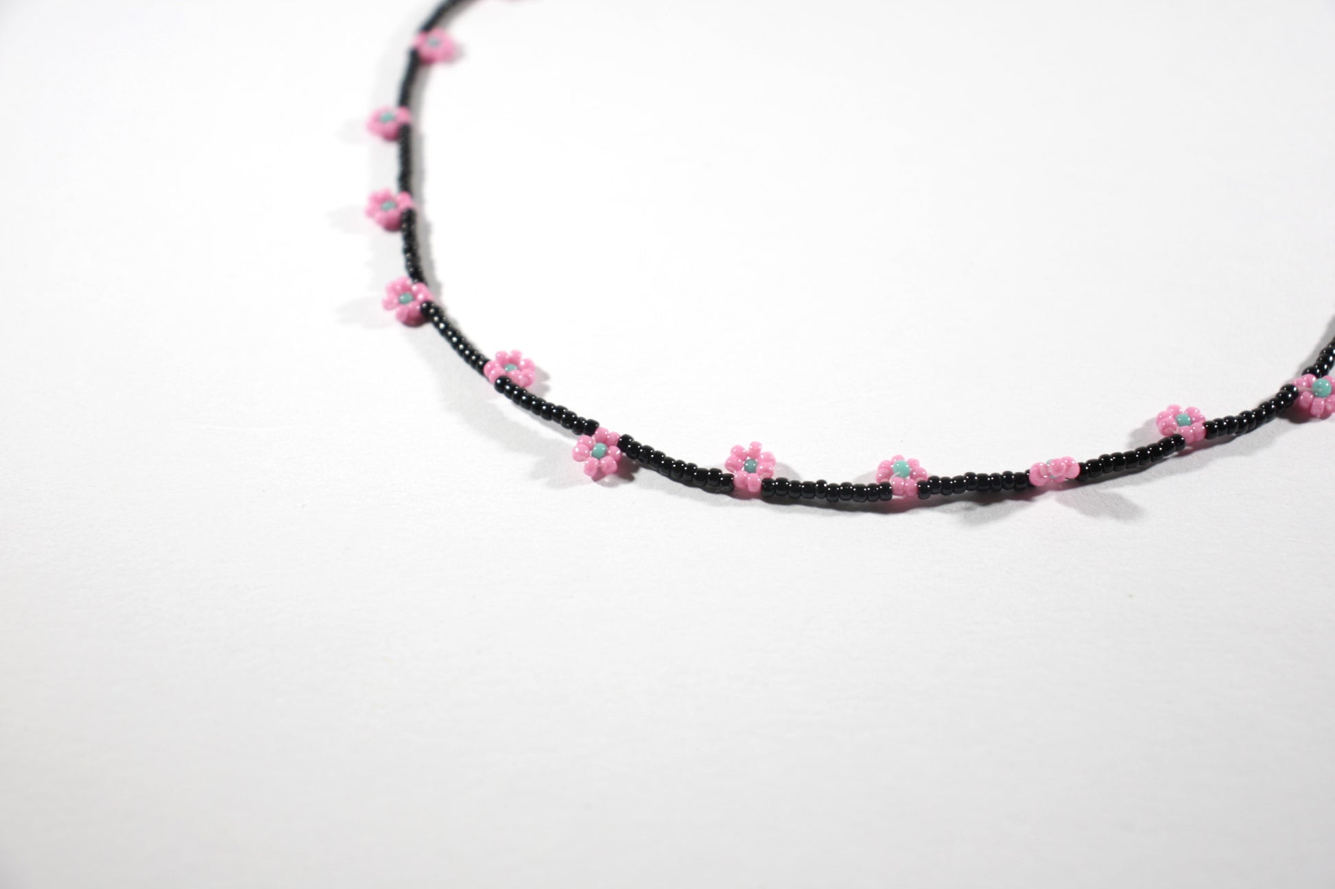 Daisy chain choker necklace black with pink and green turquoise flowers. Päivänkakkara daisy chain choker kaulakoru musta vaaleanpunaisilla kukilla. Kukkien keskusta on vihreäturkoosi.