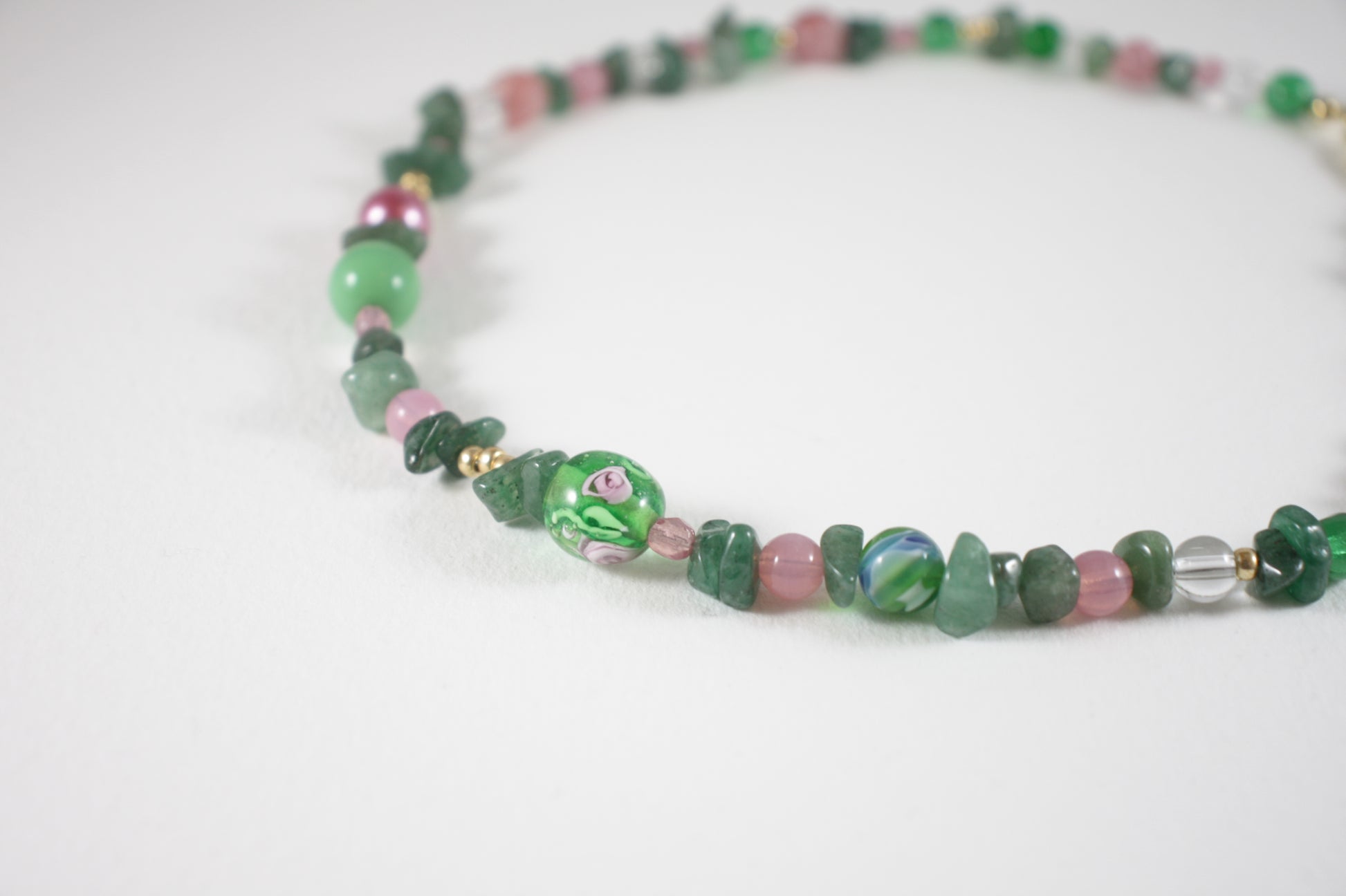 Green aventurine chips choker necklace with pink, gold color, clear and blue different sizes of glass beads. There is also gold color clasp and extension chains. 