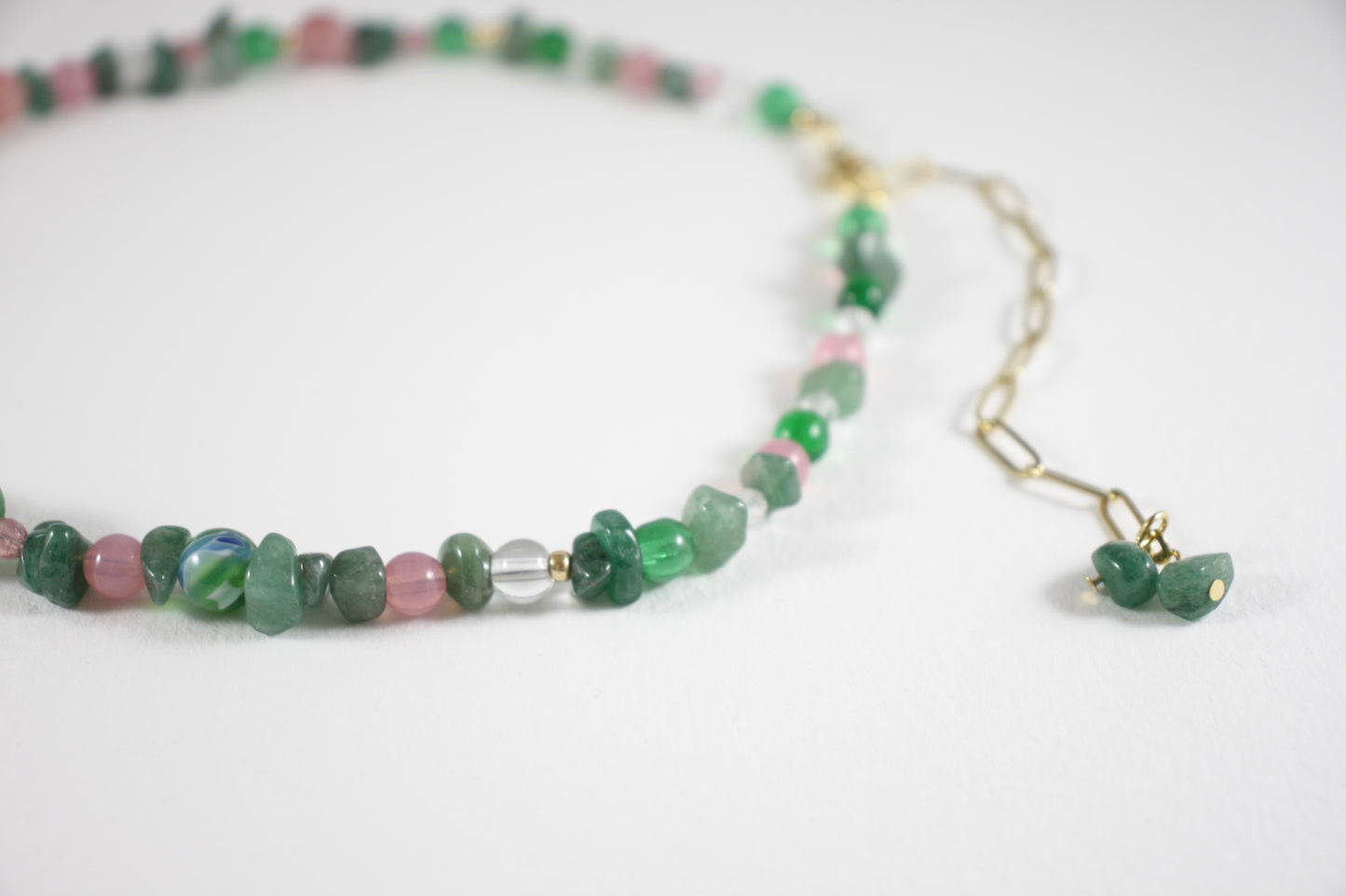 Green aventurine chips choker necklace with pink, gold color, clear and blue different sizes of glass beads. There is also gold color clasp and extension chains. 