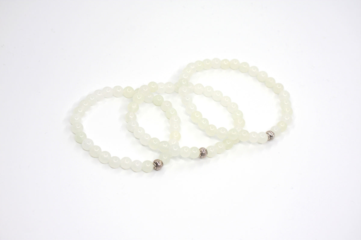 Kolme jade rannekorua valkoisella alustalla. Three jade bracelets on white setting.