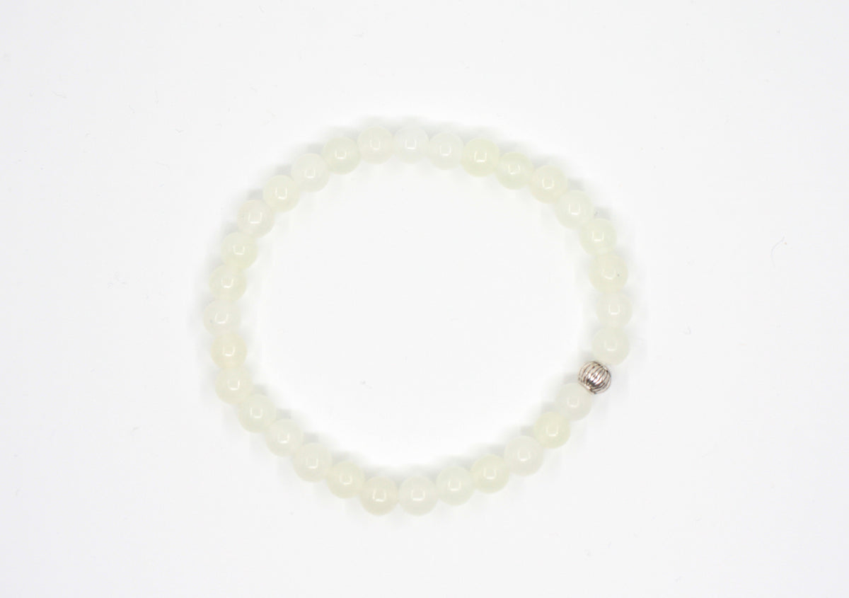 Jade rannekoru hopean värisellä helmellä. Alusta on valkoinen. Jade bracelet with one silver color bead. Bracelet is on white setting.