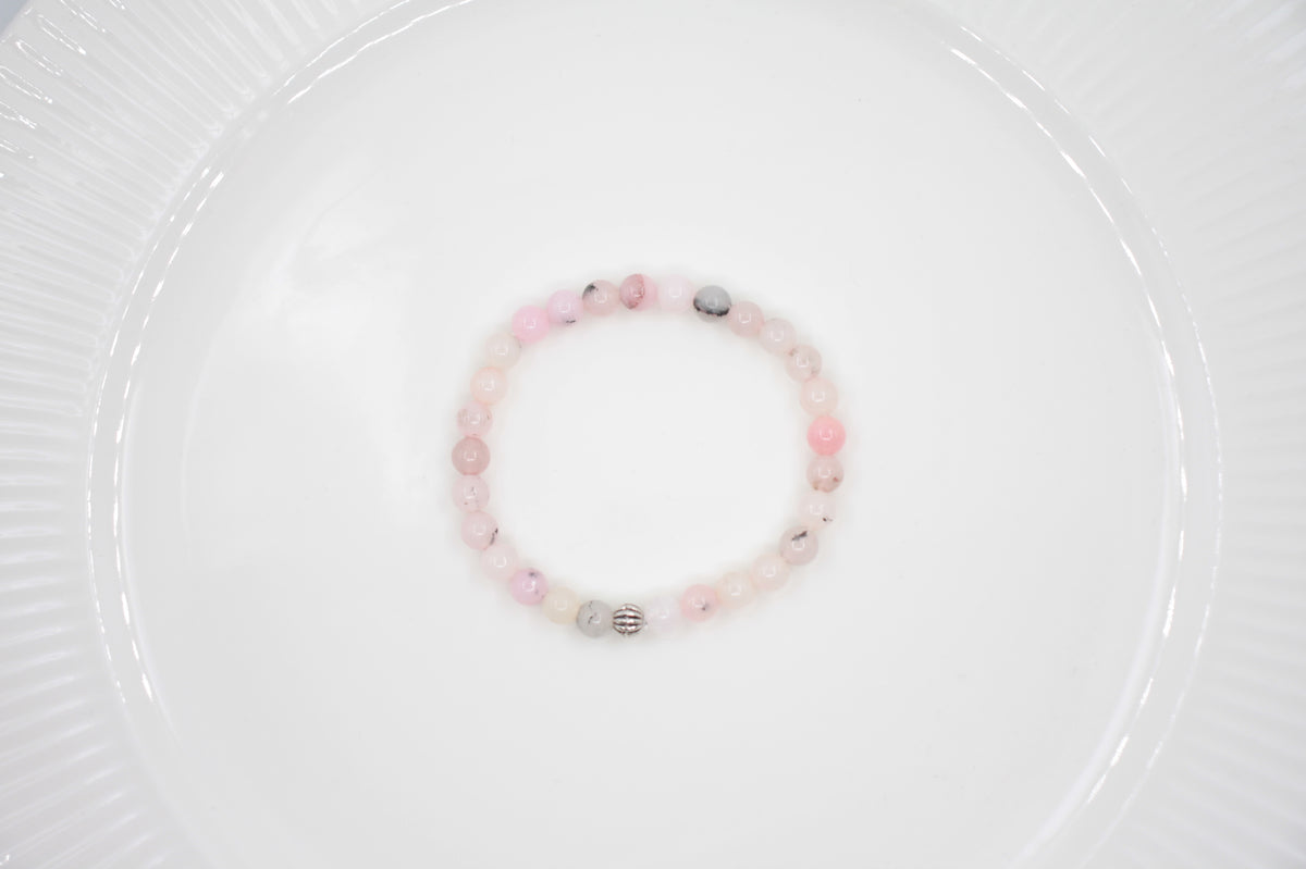 Jaspis kivihelmirannekoru vaaleanpunainen valkoisella alustalla. Pink jasper stone bead bracelet on a white surface. 