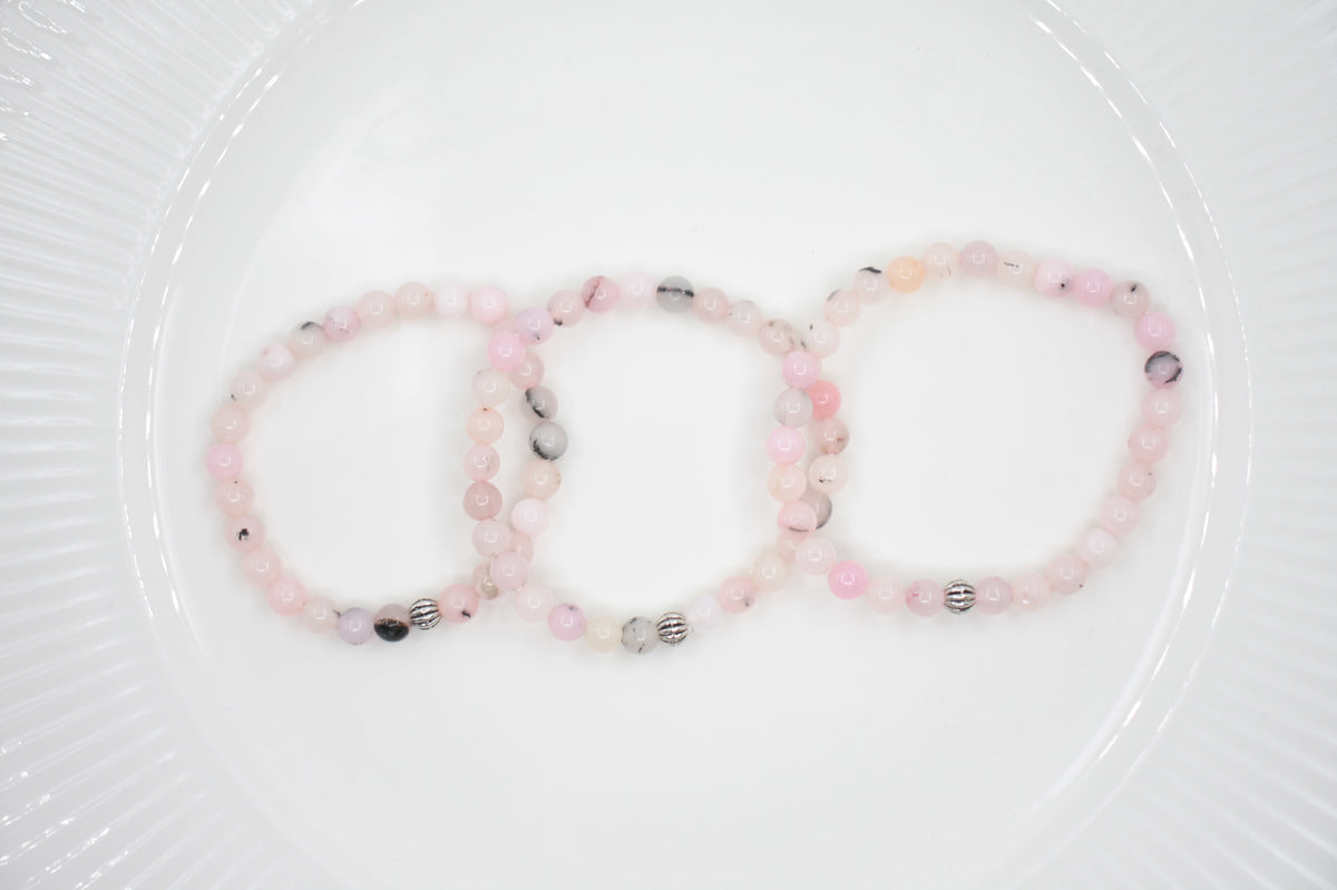 Jaspis kivihelmirannekoru vaaleanpunainen valkoisella alustalla. Pink jasper stone bead bracelet on a white surface. 