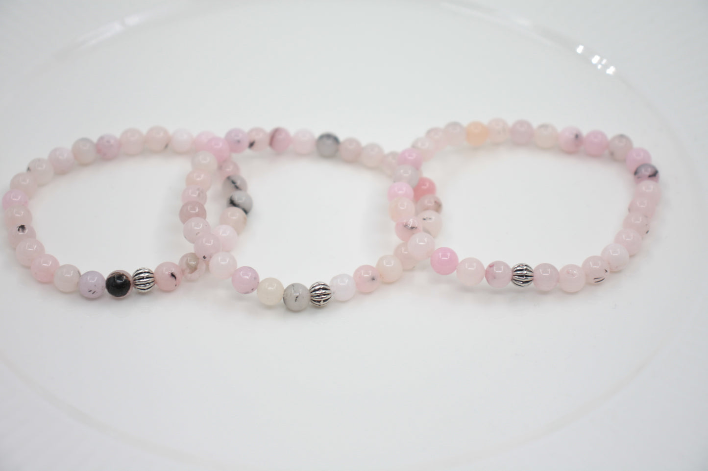 Jaspis kivihelmirannekoru vaaleanpunainen valkoisella alustalla. Pink jasper stone bead bracelet on a white surface. 