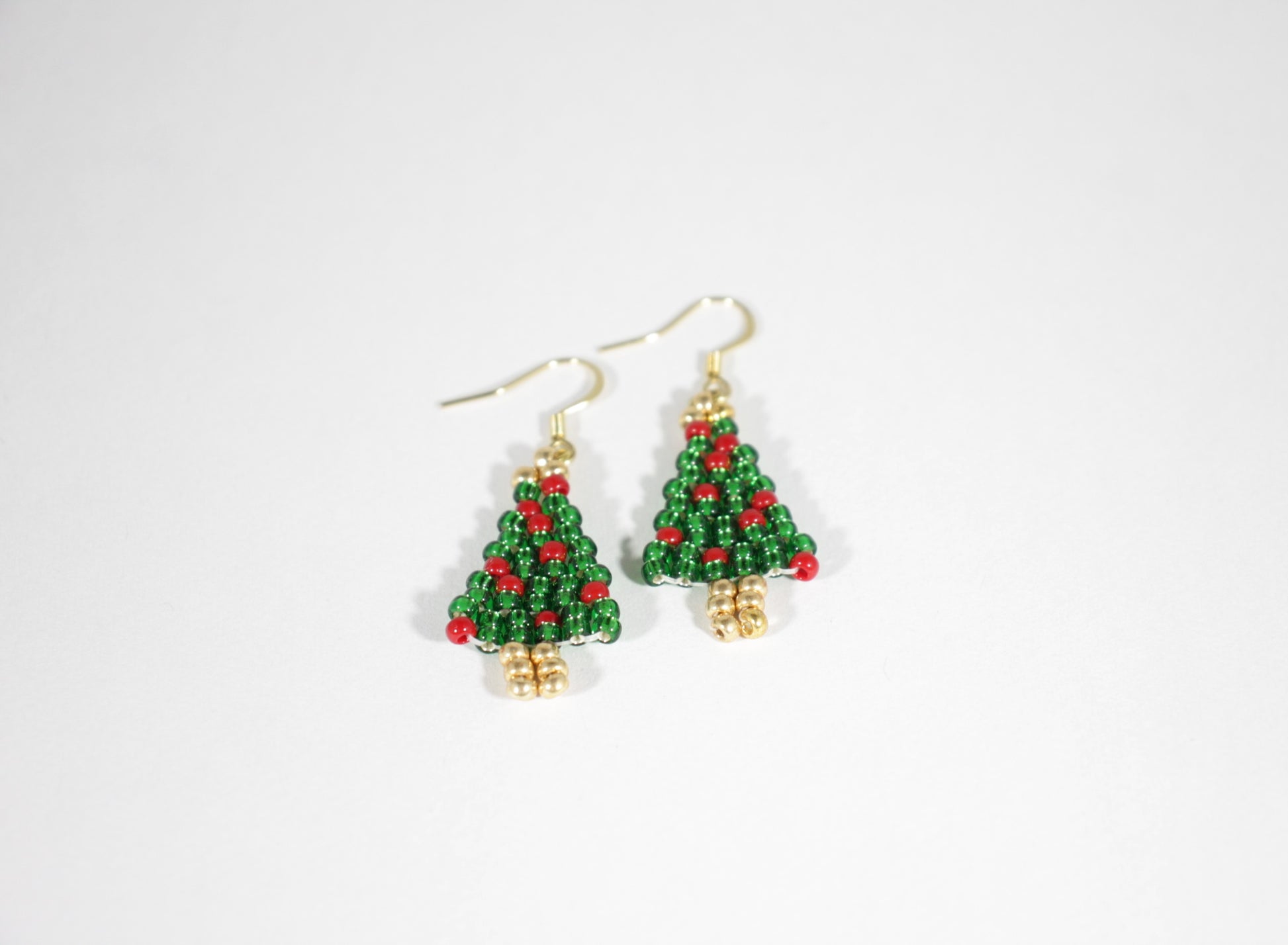 Käsintehdyt joulukuusi helmikorvakorut kimaltelevat vihreät punaisilla koristeilla. Korviksissa on kullanväriset koukut. Handmade green Christmas tree seed bead sparkling earrings with red ornaments. Hooks are gold plated stainless steel.