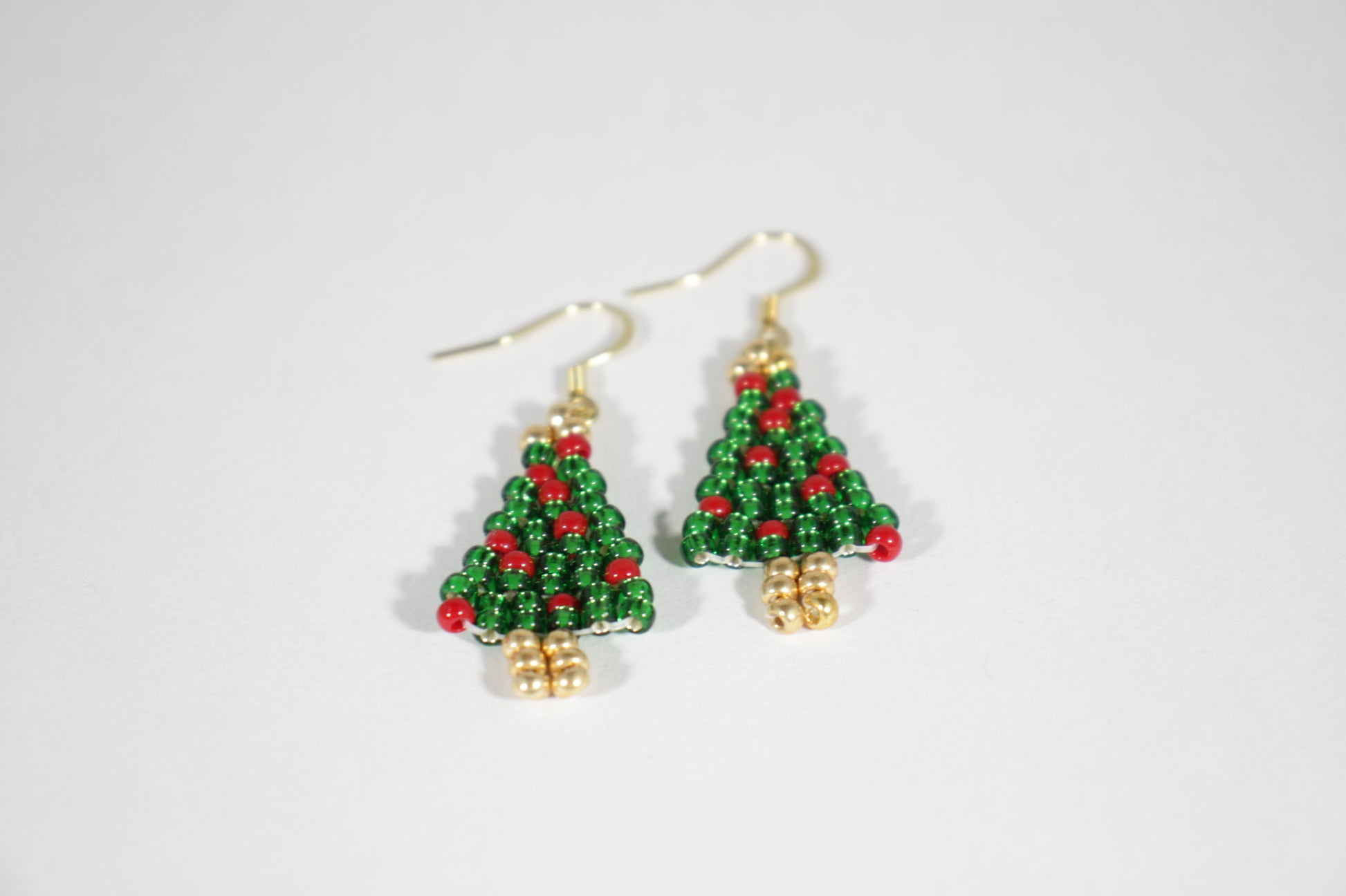 Käsintehdyt joulukuusi helmikorvakorut kimaltelevat vihreät punaisilla koristeilla. Korviksissa on kullanväriset koukut. Handmade green Christmas tree seed bead sparkling earrings with red ornaments. Hooks are gold plated stainless steel.