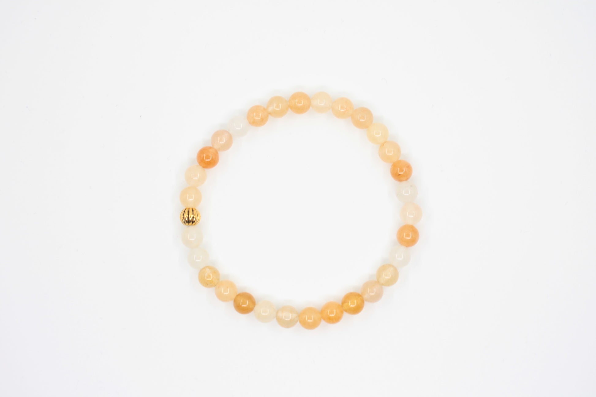 Keltainen jade joustava rannekoru kullan värisellä helmellä valkoisella alustalla. Yellow jade stretchy bracelet with gold color metal bead. Bracelet is on white background.