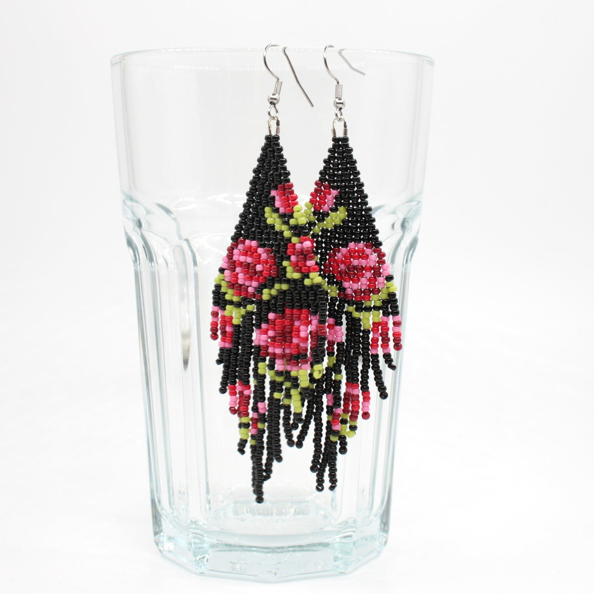 Long beaded seed bead fringe earrings hanging on the rim of drinking class. Base color of these earrings is and black and it has red roses pattern. Pitkät käsintehdyt roikkuvat helmikorvakorut roikkumassa juomalasin reunalla. Pohjaväri näissä korvakoruissa on musta sekä, kuviona punaisen eri sävyisiä ruusuja.