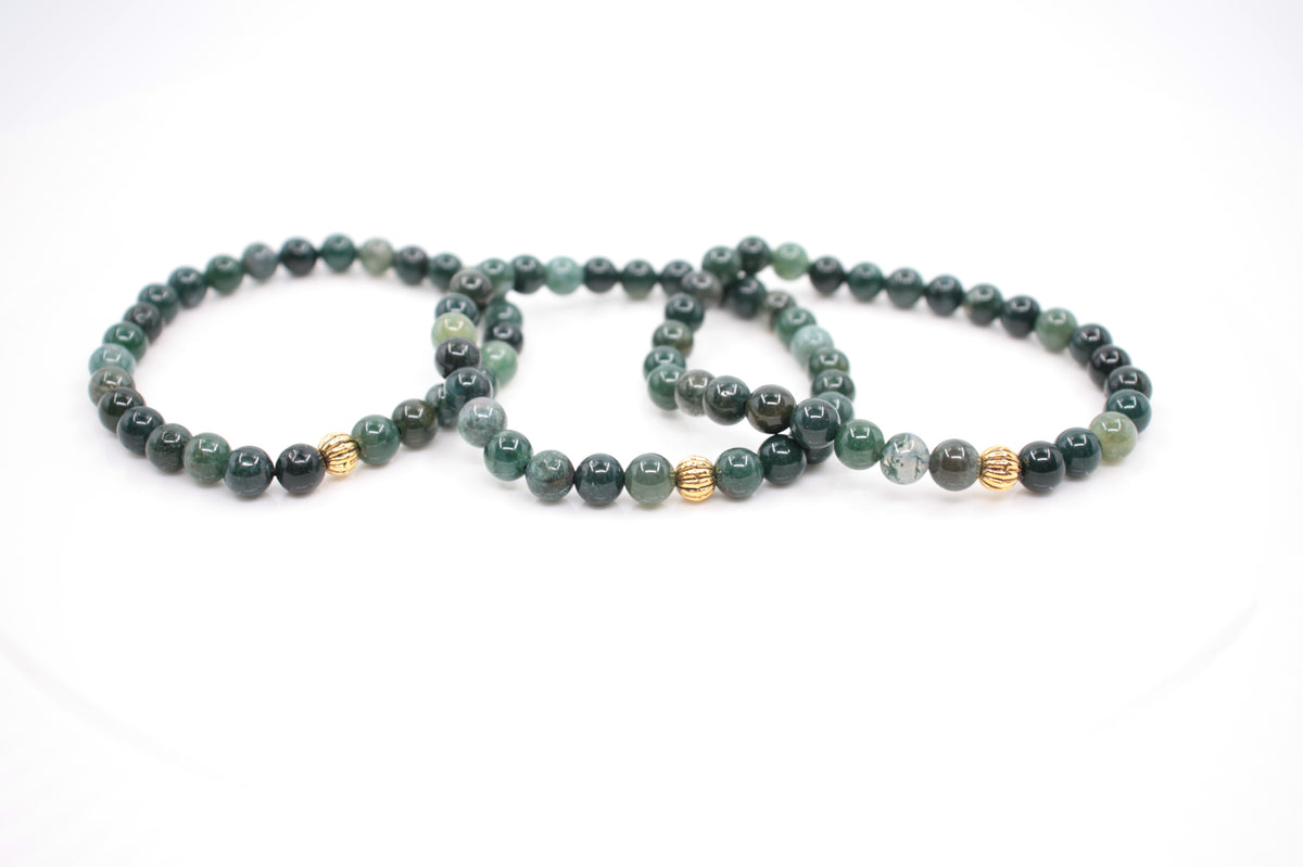 Kolme vihreää sammalakaatti rannekorua kullanvärisellä metallihelmellä. Tausta on valkoinen. Three green moss agate bracelet with gold color metal bead. Background is white.