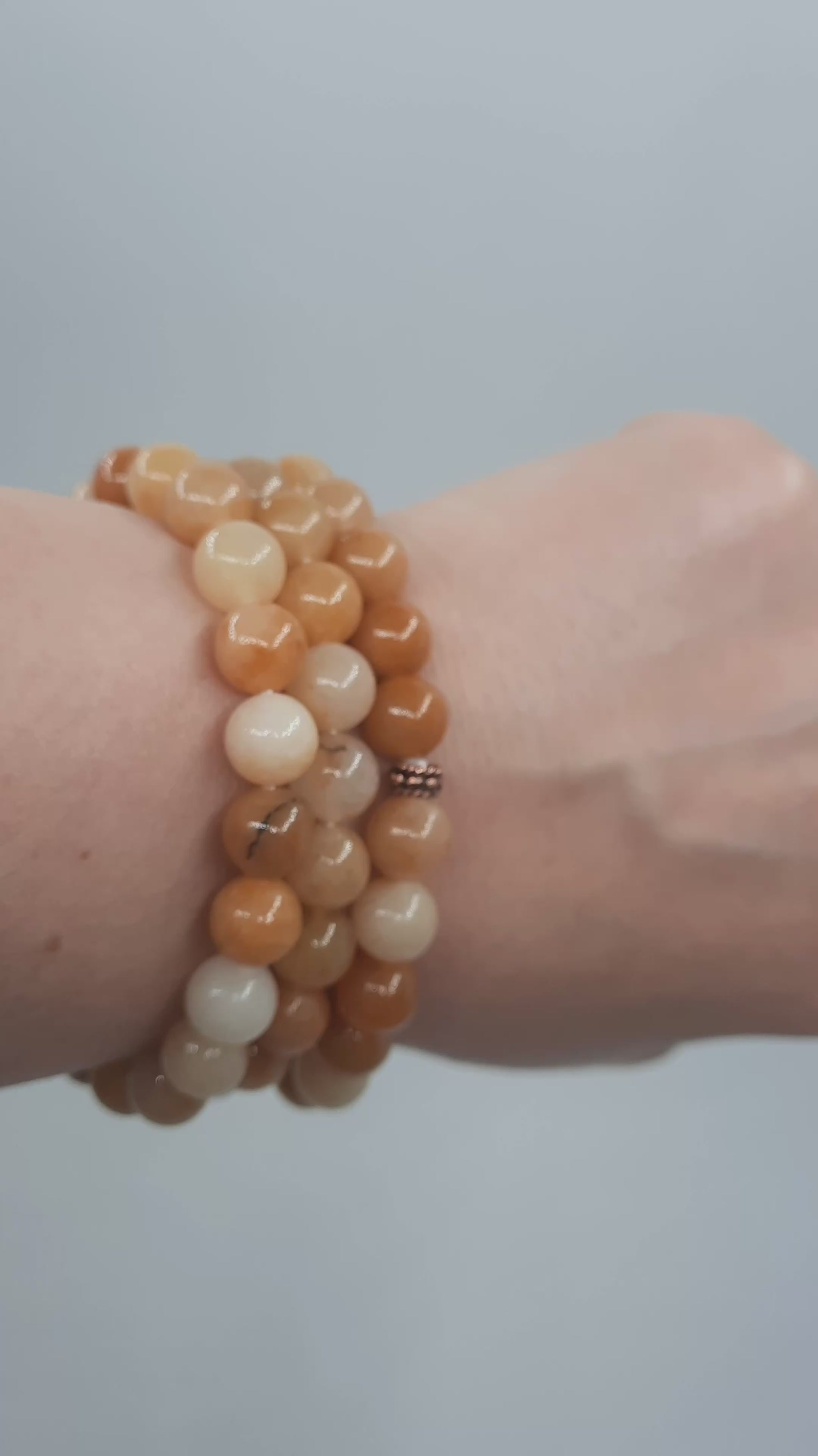 Kolme keltainen jade rannekorua esittelyssä kädessä. Three yellow jade bracelets in the spotlight on the hand.