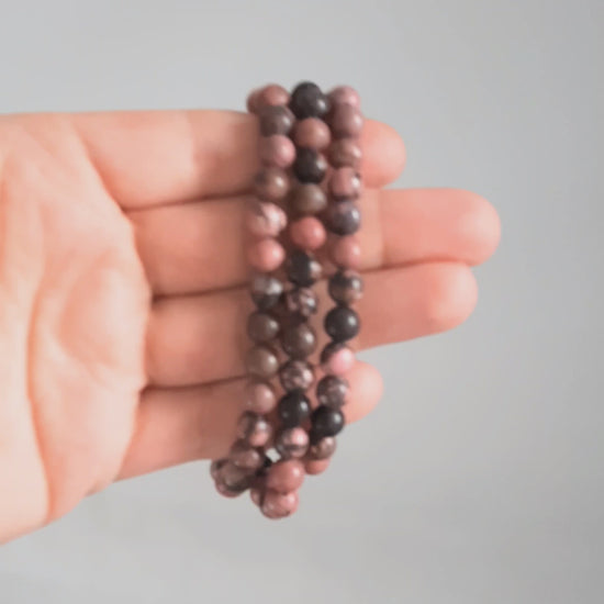 Kolme rodoniitti rannekorua esittelyssä kädessä. Three rhodonite bracelets in the spotlight on the hand.