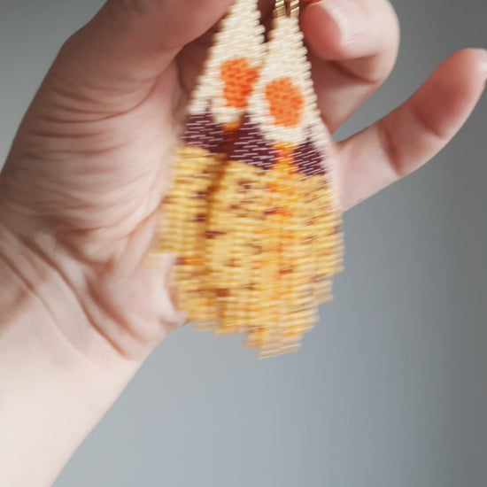 Seed bead fringe earrings with scenery pattern. Colors are brown, yellow and orange shades. Roikkuvat hapsukorvakorut pienistä lasihelmistä. Kuviona näissä korvakoruina on maisema ja värit loistavat keltaisen, ruskean ja oranssin sävyissä.