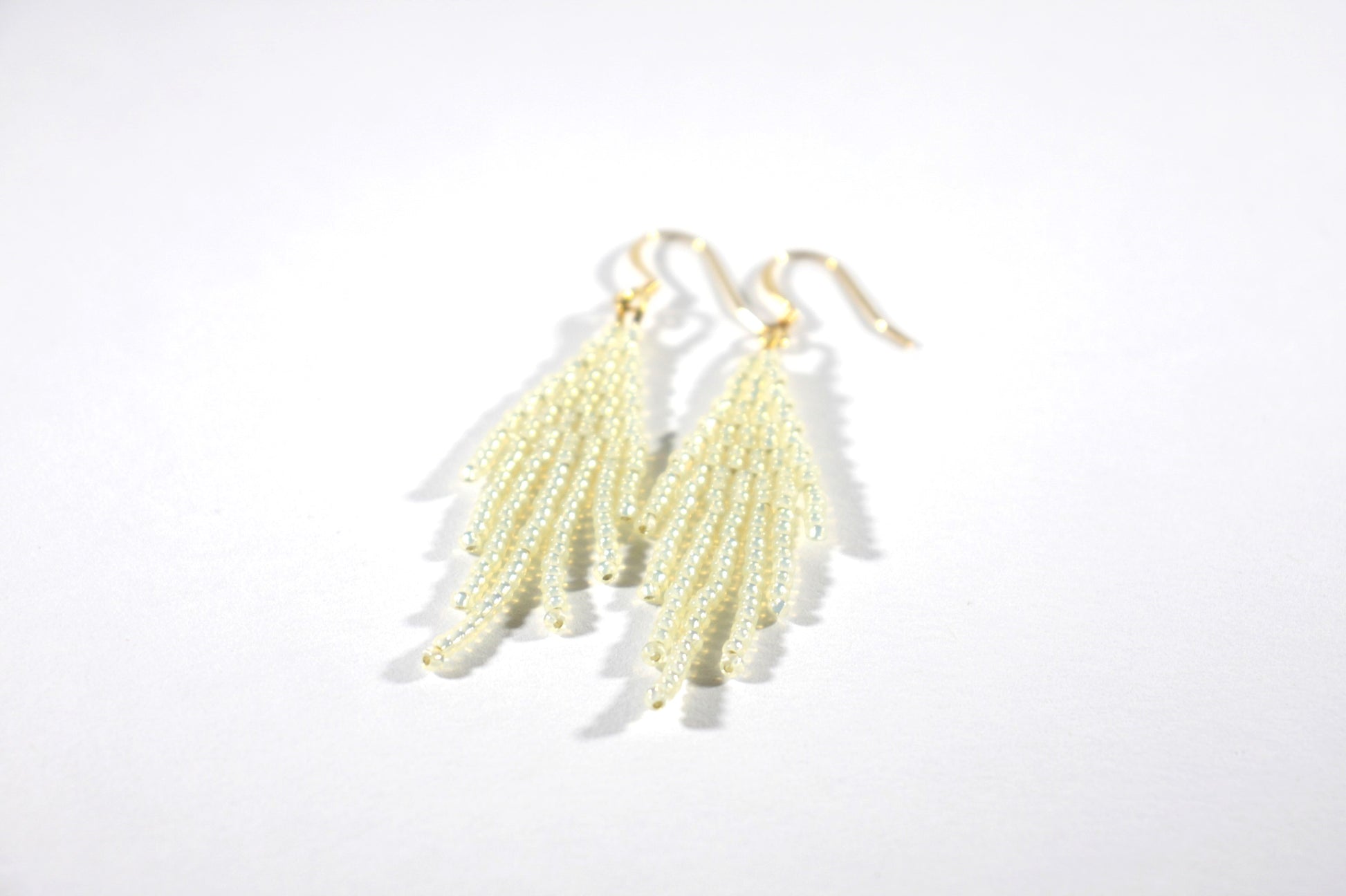 Seed bead fringe earrings sparkling cream small with gold color hooks. Lasihelmistä tehdyt pienet hapsukorvakorut väriltään kimalteleva kerma. Koulut ovat kullattua nikkelitöntä korumetallia.