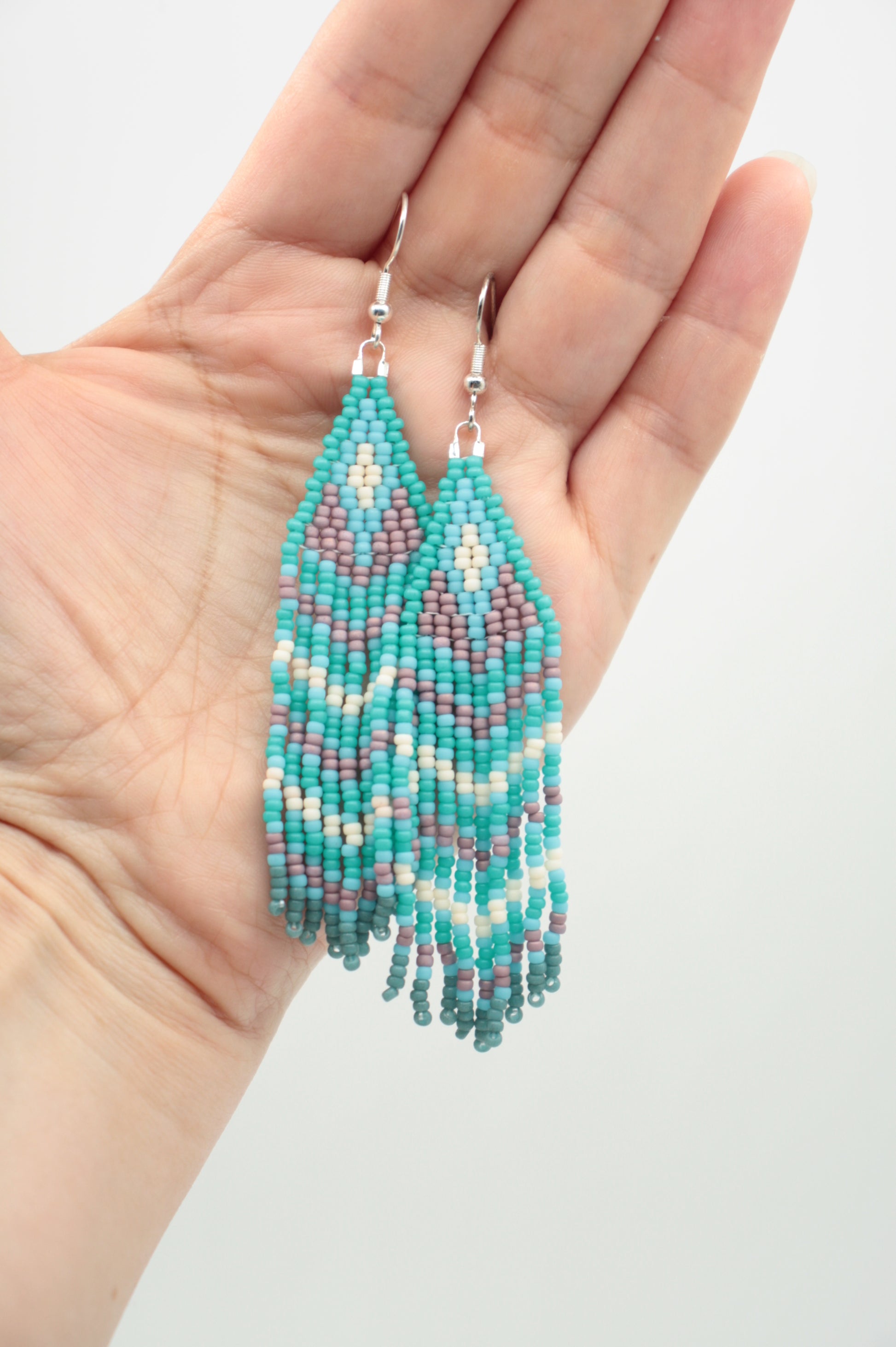 Roikkuvat hapsulliset lasihelmikorvakorut. Väreinä vihreäturkoosi, turkoosi, valkoinen ja kanerva. Seed bead fringe earrings with green turquoise, turquoise, white and purple color.