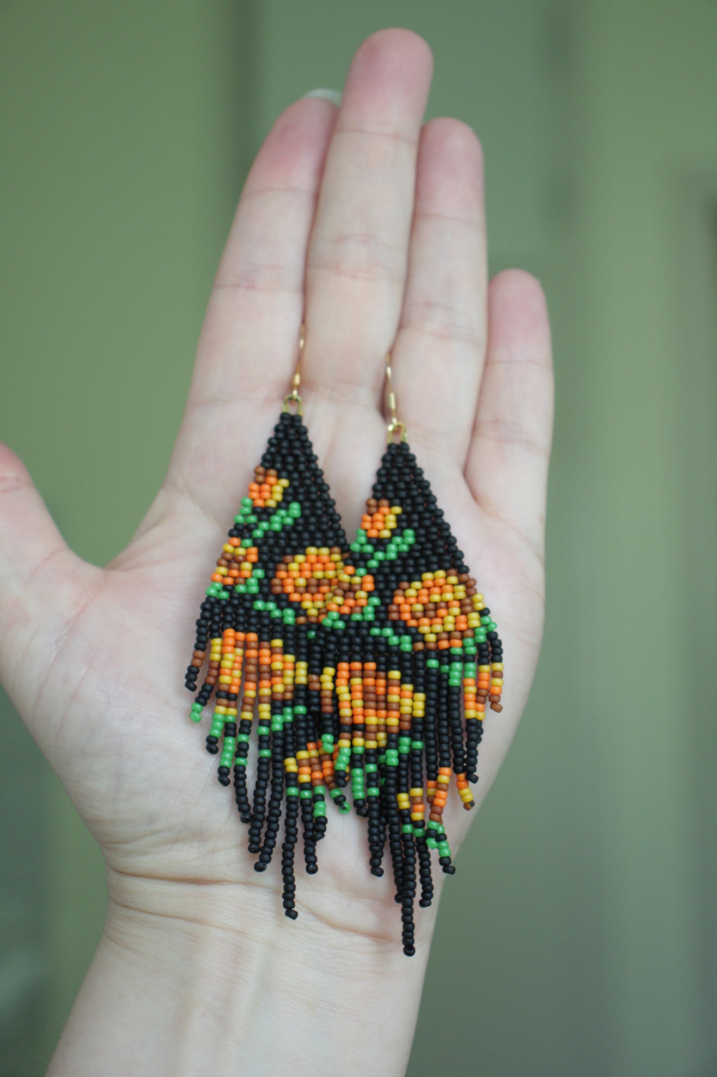 Seed bead fringe earrings matte black wit orange brown roses pattern. Pitkät roikkuvat hapsuhelmikorvakorut. Pohjaväri on mattamusta, jossa oranssin ja ruskean sävyisiä ruusukuvioita.
