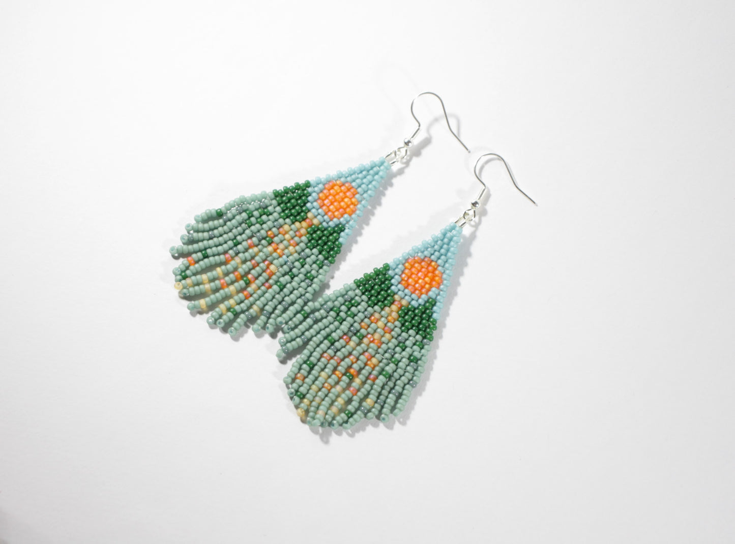 Seed bead fringe earrings with landscape pattern. Colors are turquoise, blue and orange. Roikkuvat boho helmikorvakorut maisema kuviolla. Väreinä ovat turkoosi, sininen, vihreä ja oranssi.