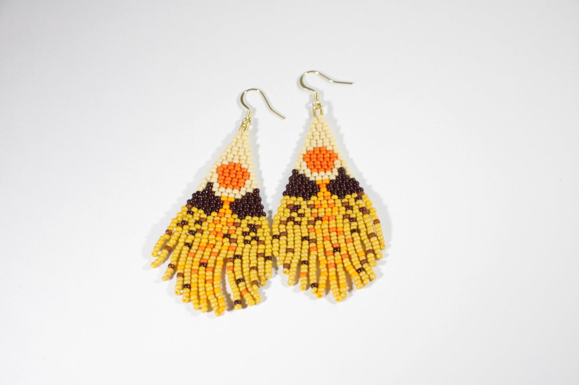 Seed bead fringe earrings with scenery pattern. Colors are brown, yellow and orange shades. Roikkuvat hapsukorvakorut pienistä lasihelmistä. Kuviona näissä korvakoruina on maisema ja värit loistavat keltaisen, ruskean ja oranssin sävyissä.