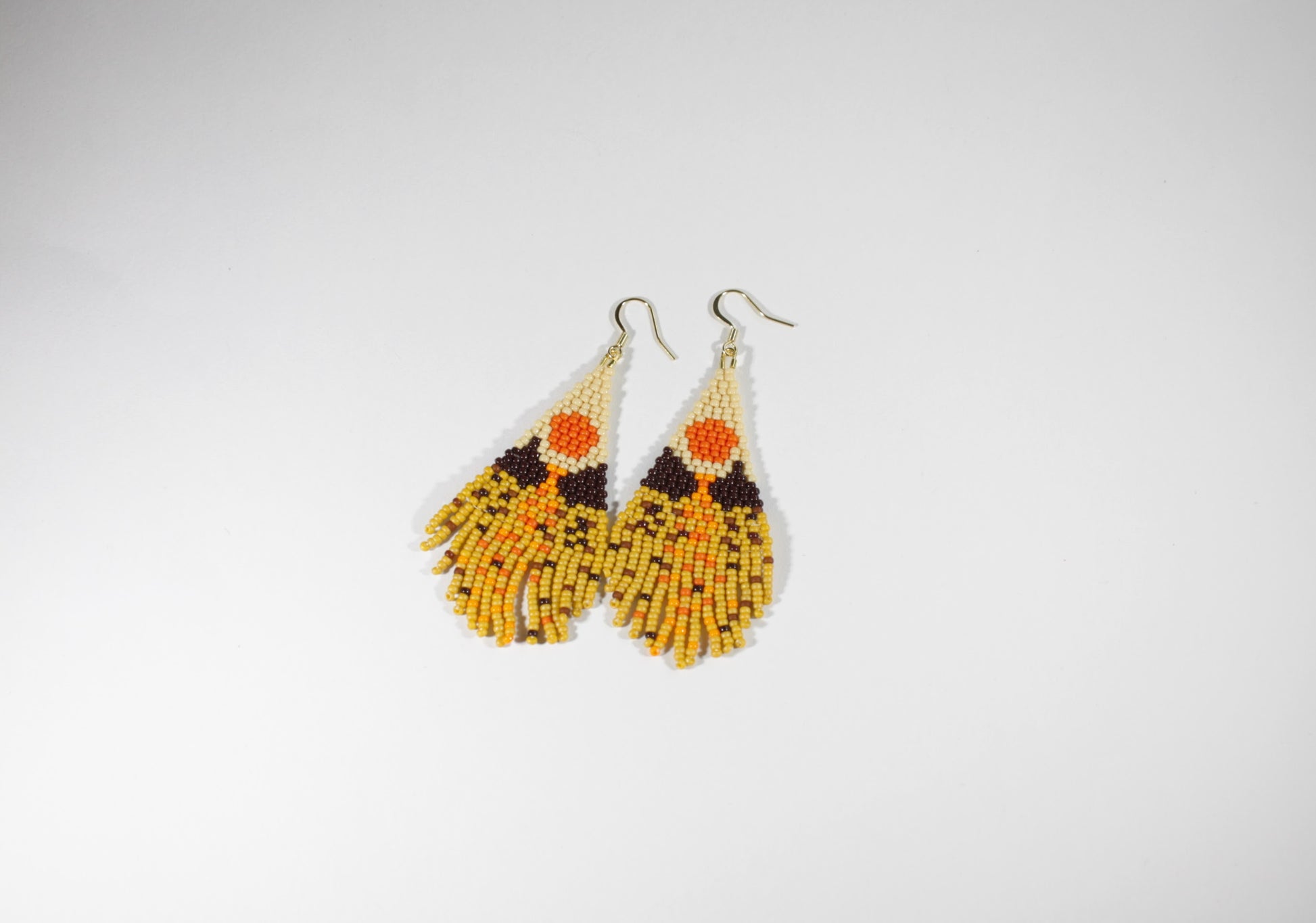 Seed bead fringe earrings with scenery pattern. Colors are brown, yellow and orange shades. Roikkuvat hapsukorvakorut pienistä lasihelmistä. Kuviona näissä korvakoruina on maisema ja värit loistavat keltaisen, ruskean ja oranssin sävyissä.