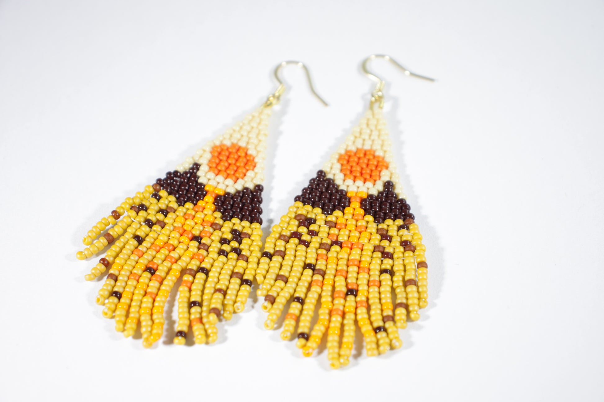 Seed bead fringe earrings with scenery pattern. Colors are brown, yellow and orange shades. Roikkuvat hapsukorvakorut pienistä lasihelmistä. Kuviona näissä korvakoruina on maisema ja värit loistavat keltaisen, ruskean ja oranssin sävyissä.