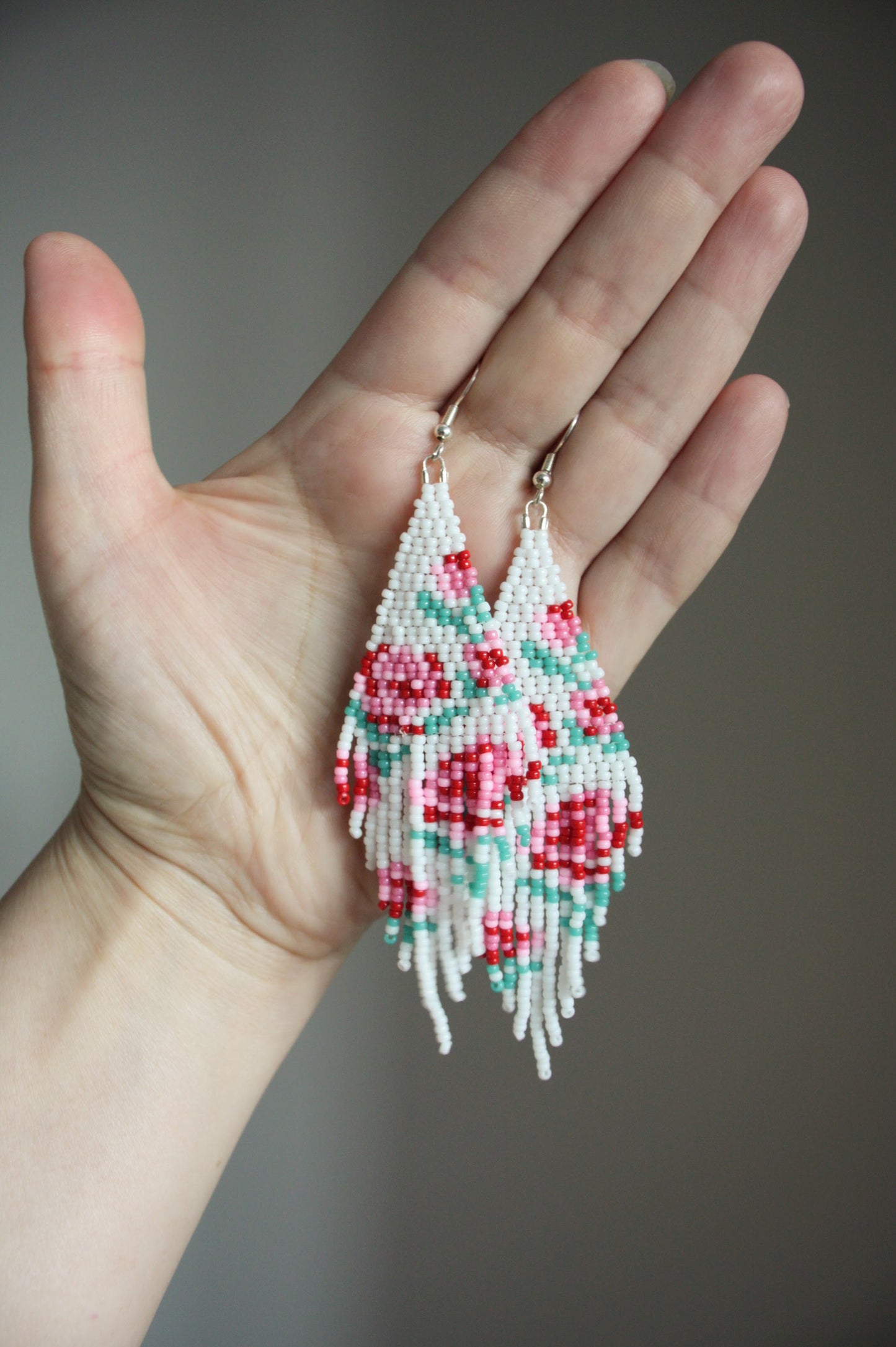 Long beaded seed bead fringe earrings. Base color of these earrings is white and has red and pink roses pattern. Pitkät käsintehdyt roikkuvat helmikorvakorut. Pohjaväri näissä korvakoruissa on valkoinen sekä, kuviona on punaisia ja pinkkejä ruusuja.  
