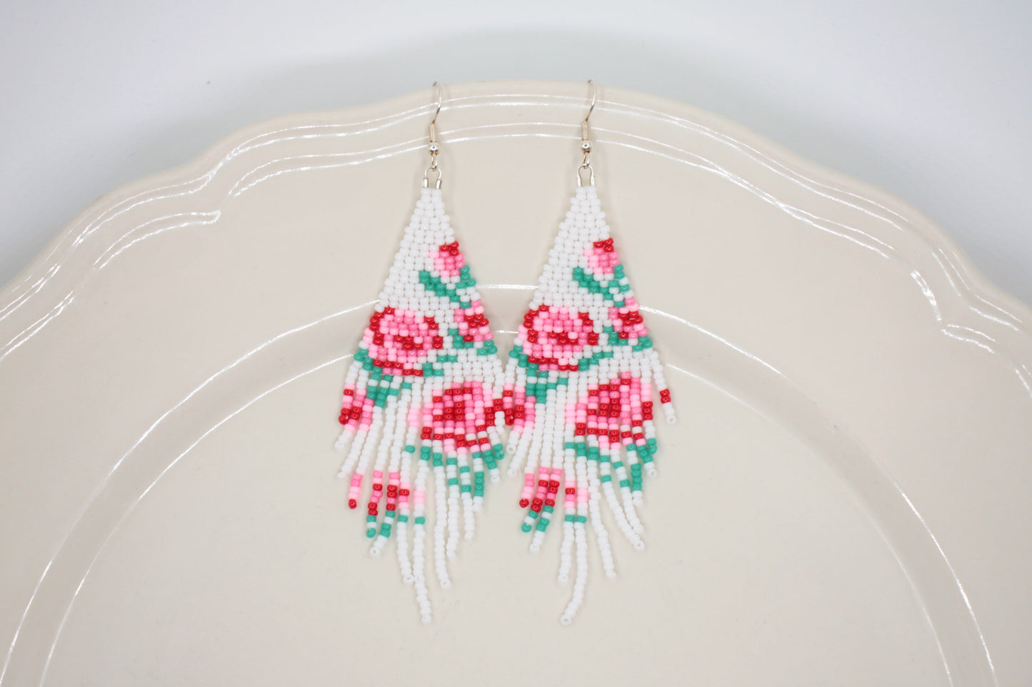 Long beaded seed bead fringe earrings. Base color of these earrings is white and has red and pink roses pattern. Pitkät käsintehdyt roikkuvat helmikorvakorut. Pohjaväri näissä korvakoruissa on valkoinen sekä, kuviona on punaisia ja pinkkejä ruusuja.  