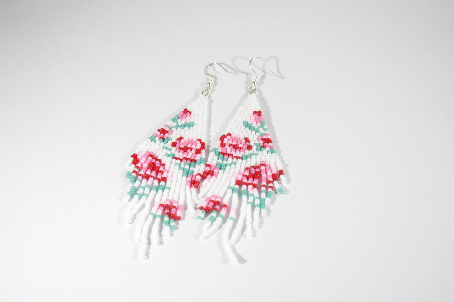 Long beaded seed bead fringe earrings. Base color of these earrings is white and has red and pink roses pattern. Pitkät käsintehdyt roikkuvat helmikorvakorut. Pohjaväri näissä korvakoruissa on valkoinen sekä, kuviona on punaisia ja pinkkejä ruusuja.  