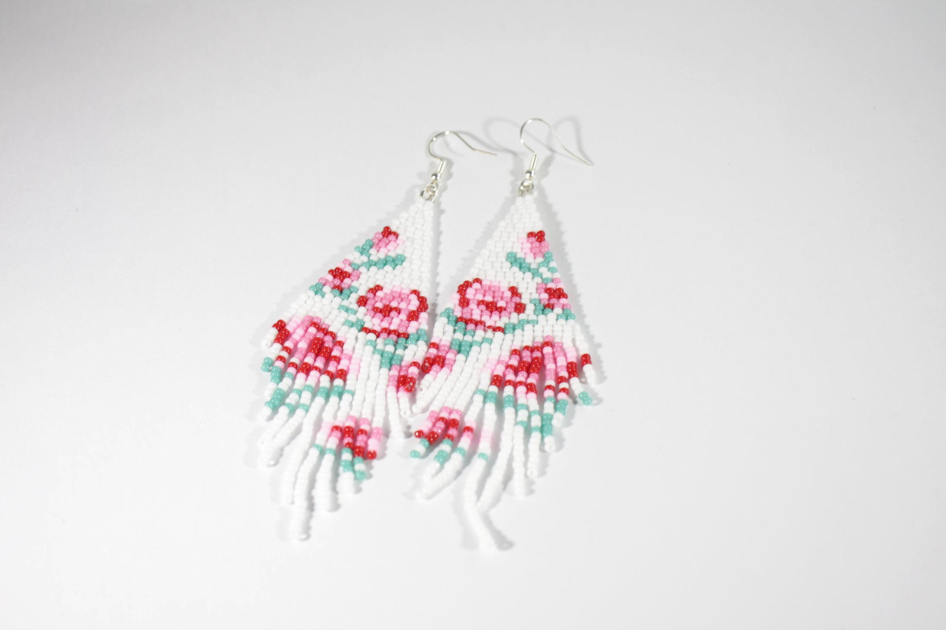 Long beaded seed bead fringe earrings. Base color of these earrings is white and has red and pink roses pattern. Pitkät käsintehdyt roikkuvat helmikorvakorut. Pohjaväri näissä korvakoruissa on valkoinen sekä, kuviona on punaisia ja pinkkejä ruusuja.  