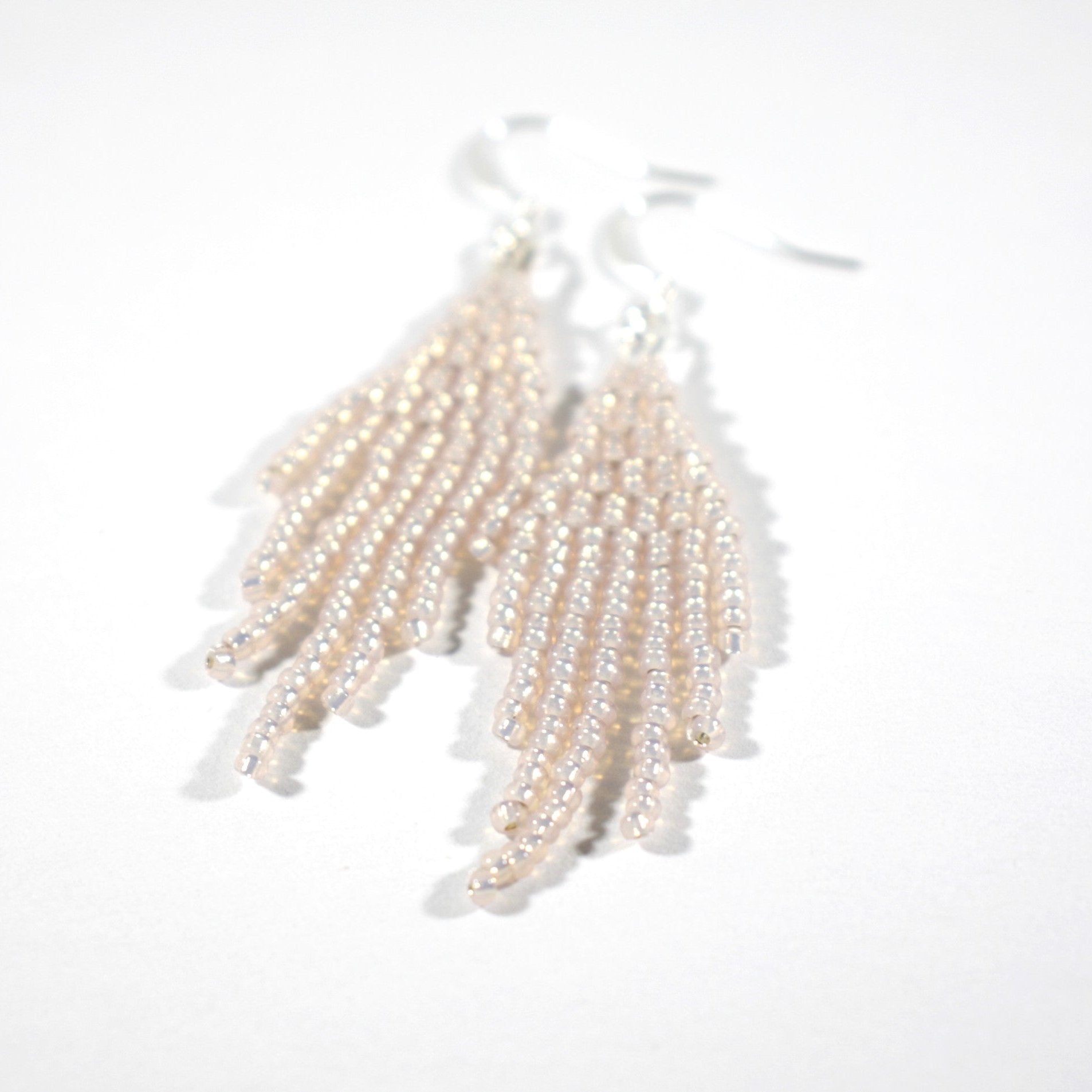 Seed bead fringe earrings small sparkling light rose with silver color hooks. Pienistä lasihelmistä kudotut roikkuvat hapsulliset korvakorut väriltään kimalteleva vaalea ruusu. Korvakoruissa on hopeanväriset koukut.