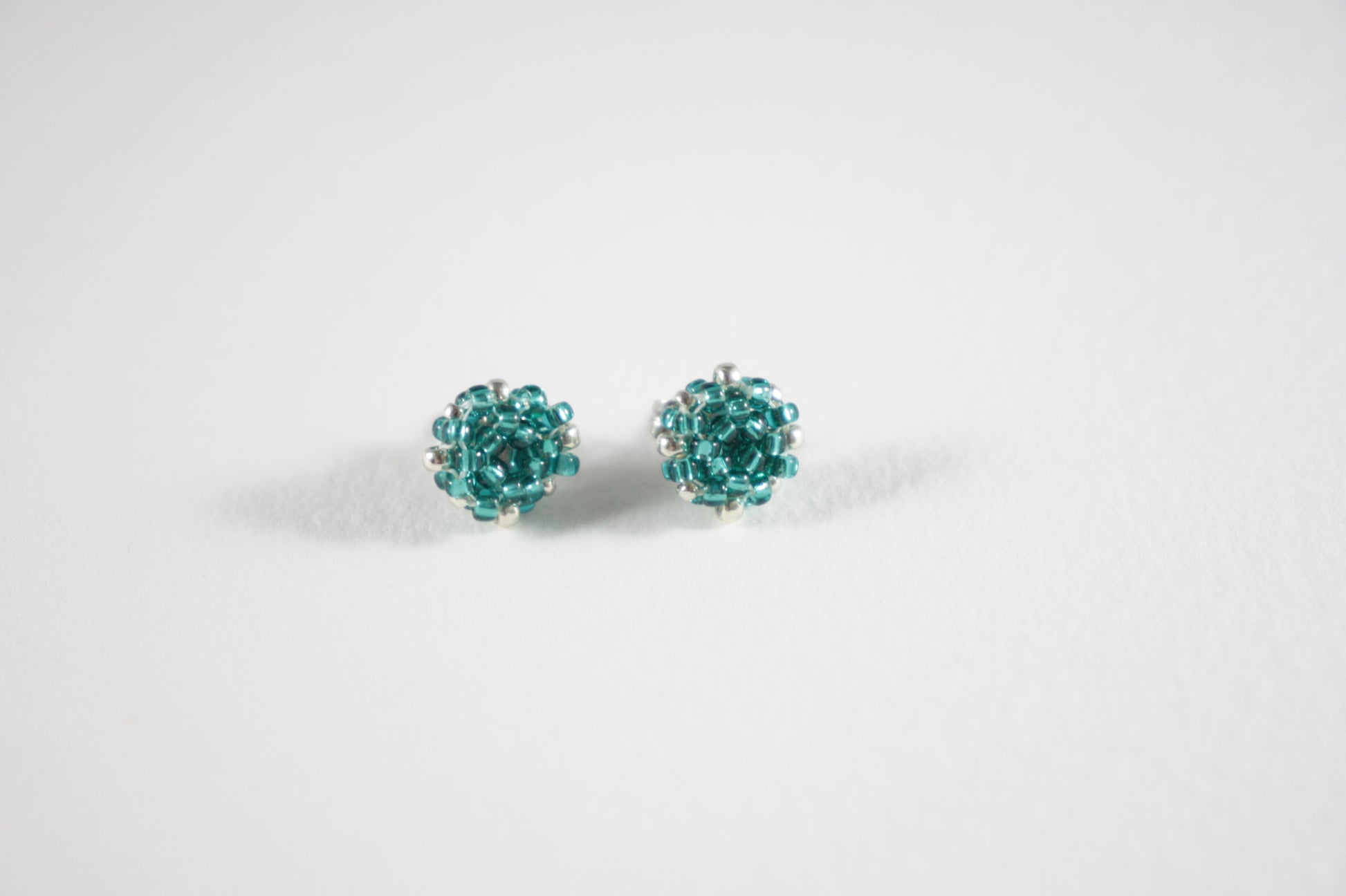 Seed bead stud earrings teal green turquoise and silver color with stainless steel stud.