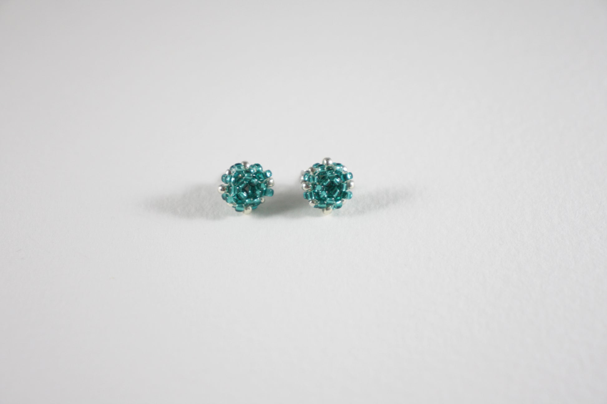 Seed bead stud earrings teal green turquoise and silver color with stainless steel stud.