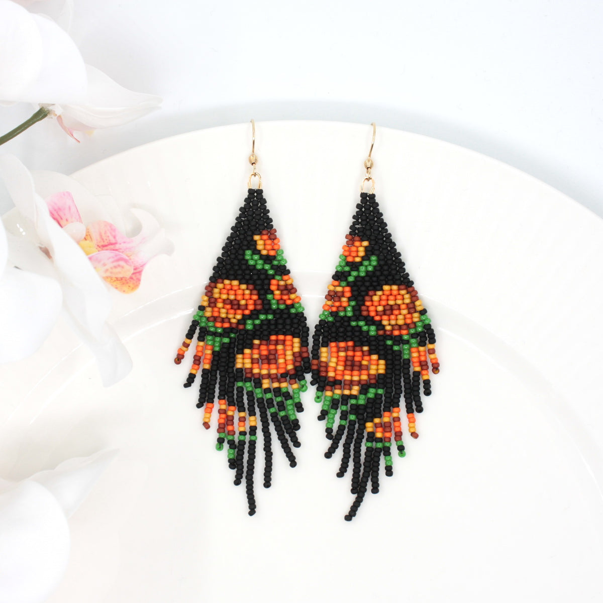 Seed bead fringe earrings matte black wit orange brown roses pattern. Pitkät roikkuvat hapsuhelmikorvakorut. Pohjaväri on mattamusta, jossa oranssin ja ruskean sävyisiä ruusukuvioita.