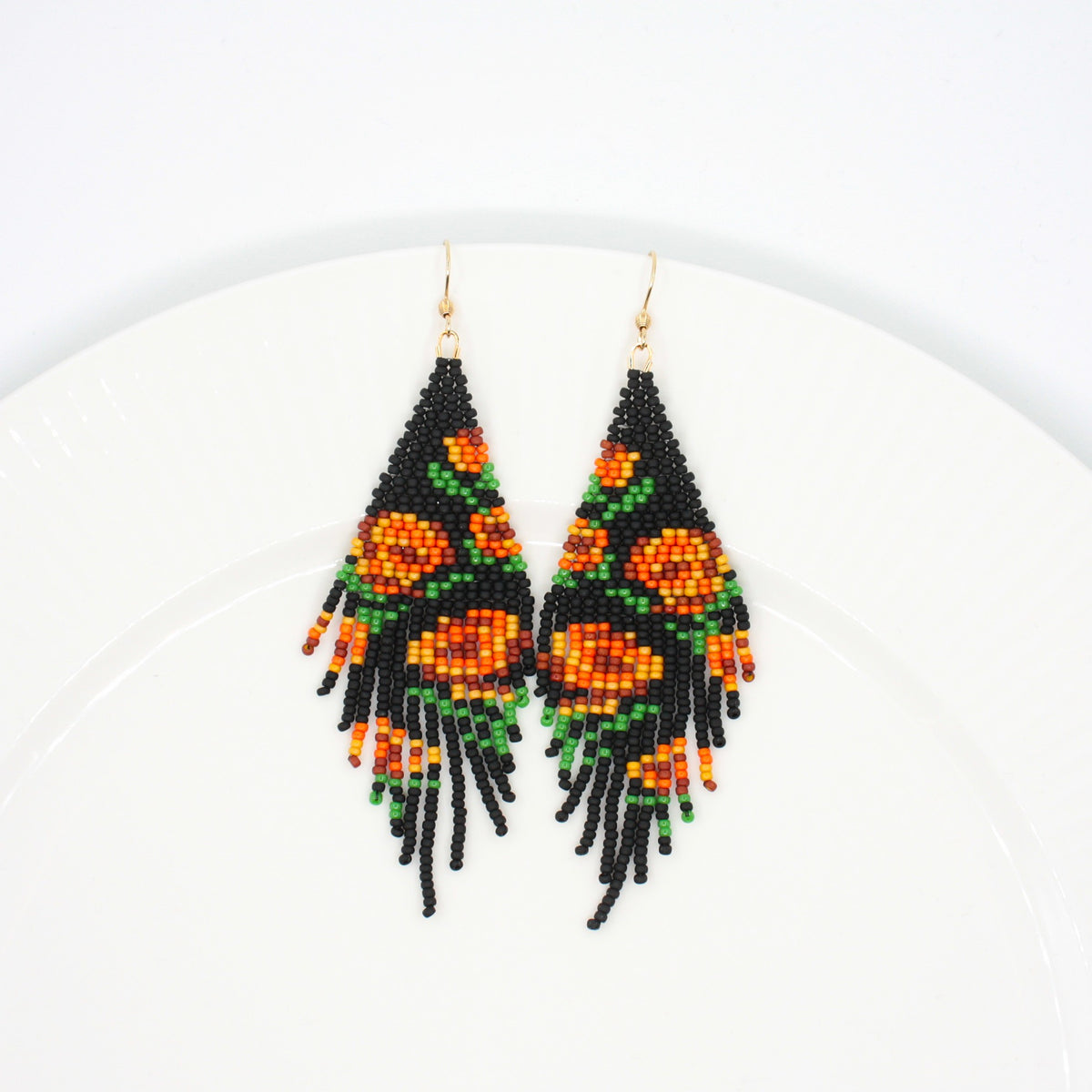 Seed bead fringe earrings matte black wit orange brown roses pattern. Pitkät roikkuvat hapsuhelmikorvakorut. Pohjaväri on mattamusta, jossa oranssin ja ruskean sävyisiä ruusukuvioita.